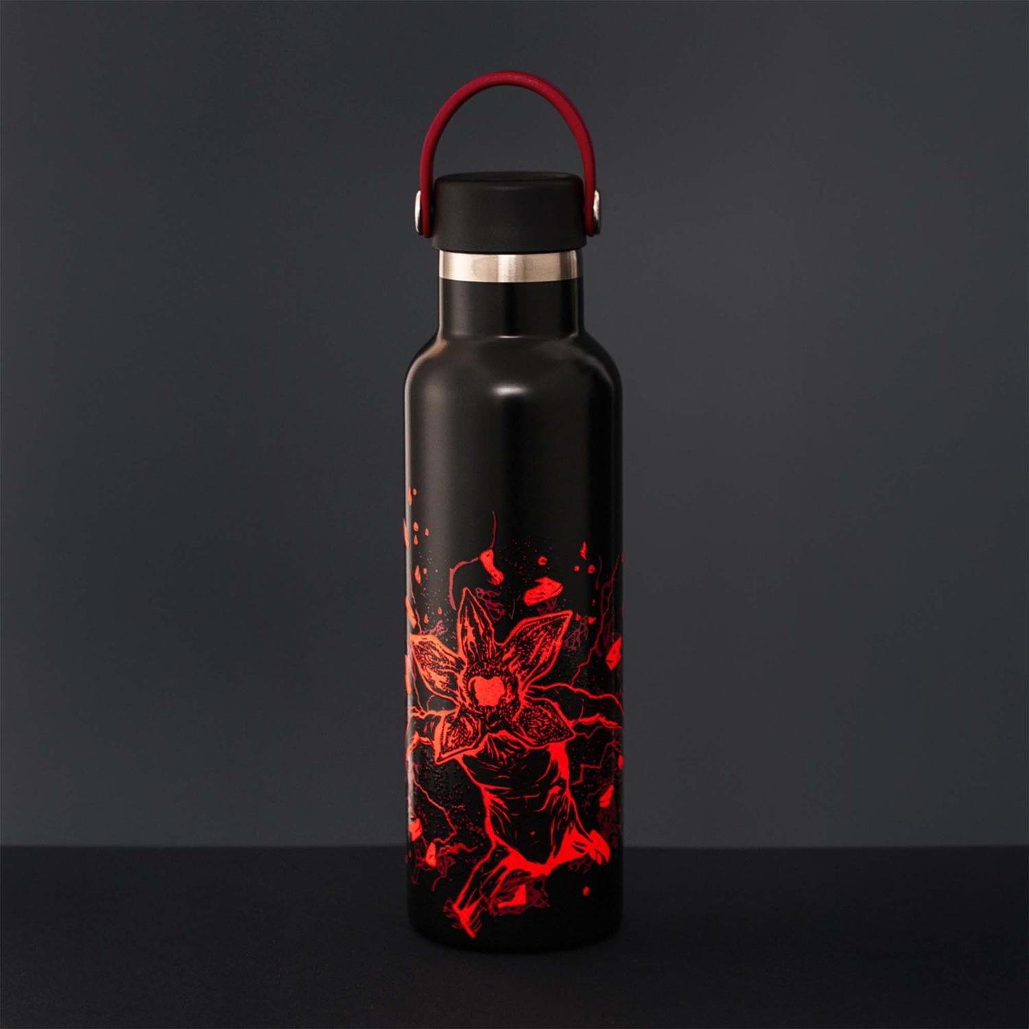 Borraccia nera con design Demogorgon rosso. Ha un manico rosso e un tappo nero. Sfondo scuro.