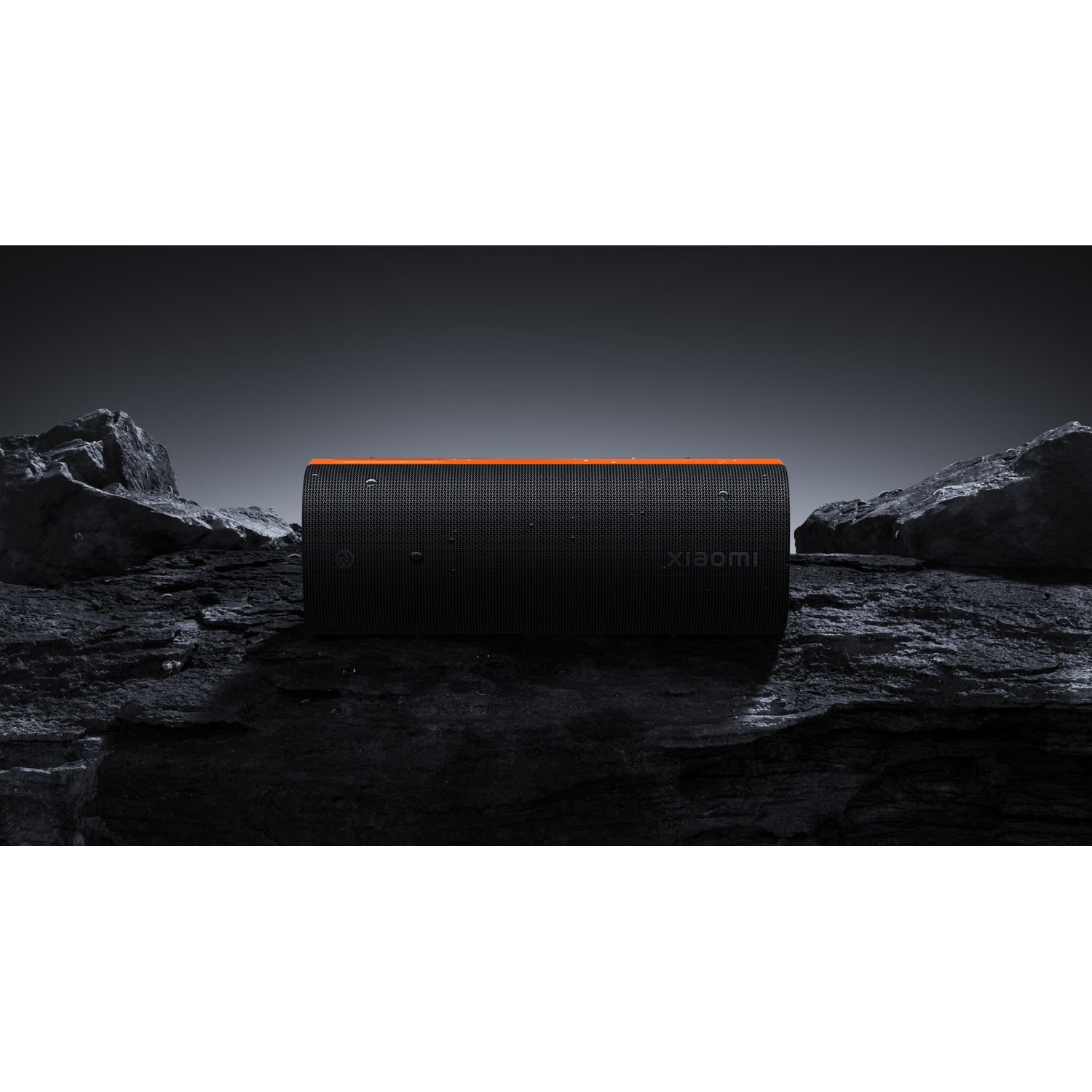 Een zwarte Xiaomi-luidspreker met een oranje streep, rustend op donkere rotsen. De achtergrond is een donkergrijze gradiënt.