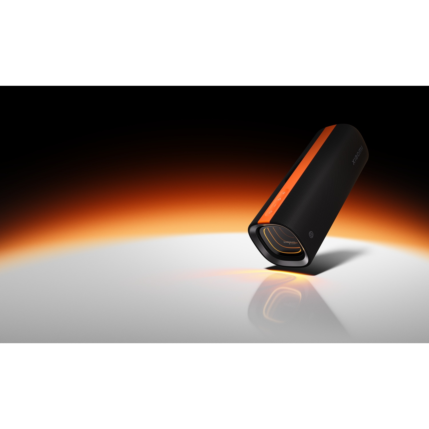 Een zwarte en oranje Xiaomi-luidspreker op een wit oppervlak met een oranje en zwarte gradiëntachtergrond. Reflecterend oppervlak.