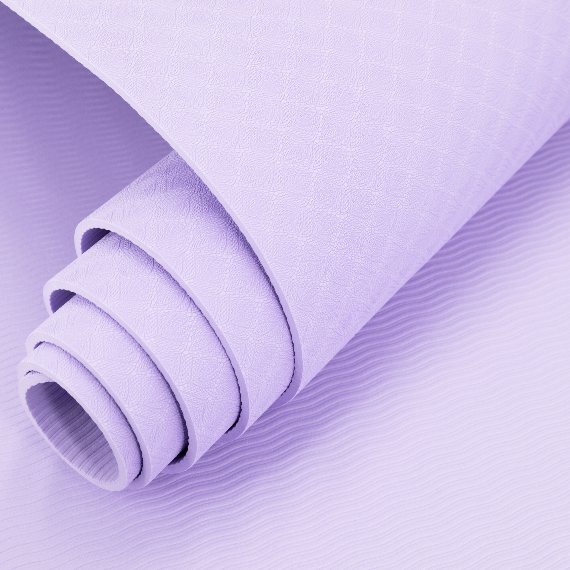 Zwinięta lawendowa mata do jogi o teksturowanej powierzchni. Tło pokazuje rozwiniętą część.