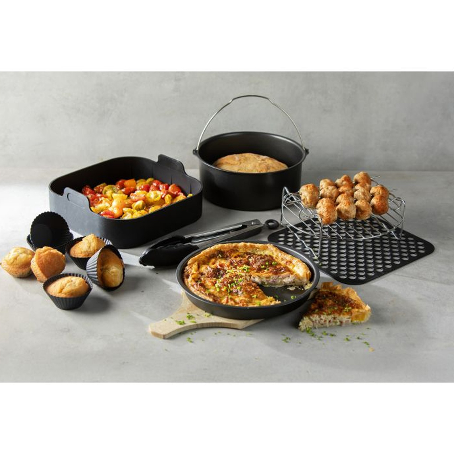 Vari cibi cotti sono disposti, tra cui muffin, quiche e spiedini. Sono presenti contenitori e utensili da cucina neri.
