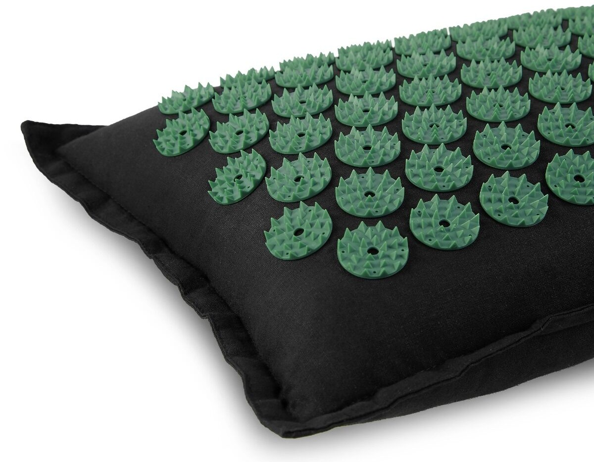 Poduszka do akupresury z zielonymi plastikowymi kolcami na czarnej poduszce z tkaniny. Białe tło. Widok z bliska.