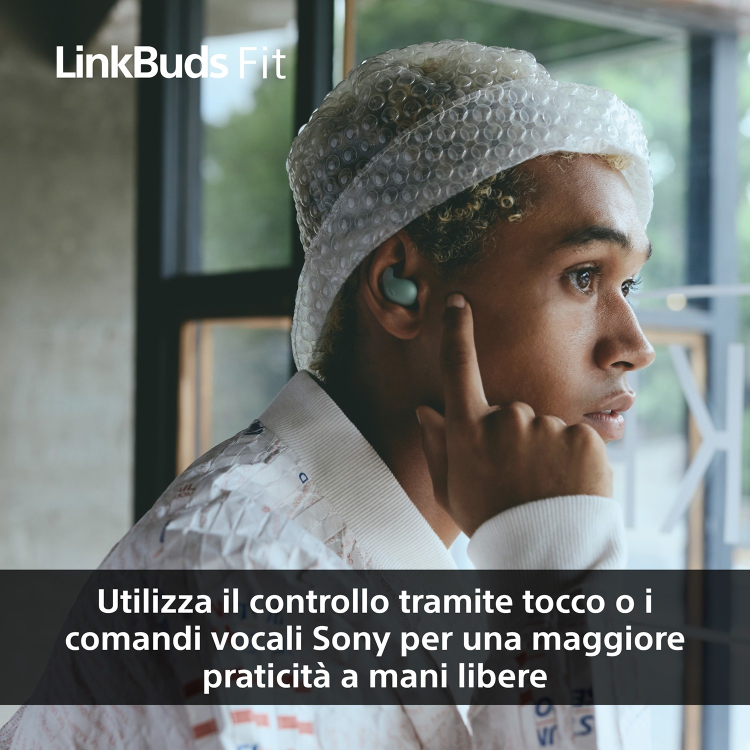 Una persona con un cappello di pluriball e auricolari si tocca l'orecchio. Sotto c'è scritto: 'Utilizza il controllo...'