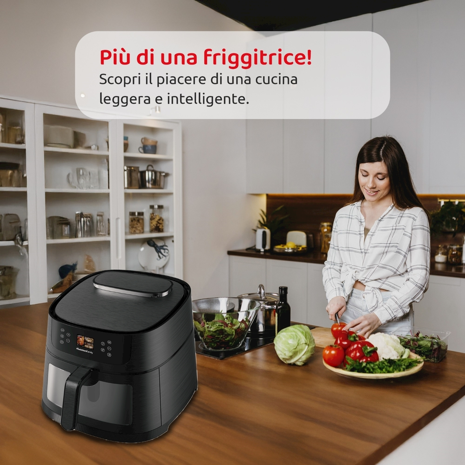 Una donna taglia verdure in cucina. Una friggitrice ad aria è sul bancone. Varie verdure sono su un piatto. Armadi sullo sfondo.