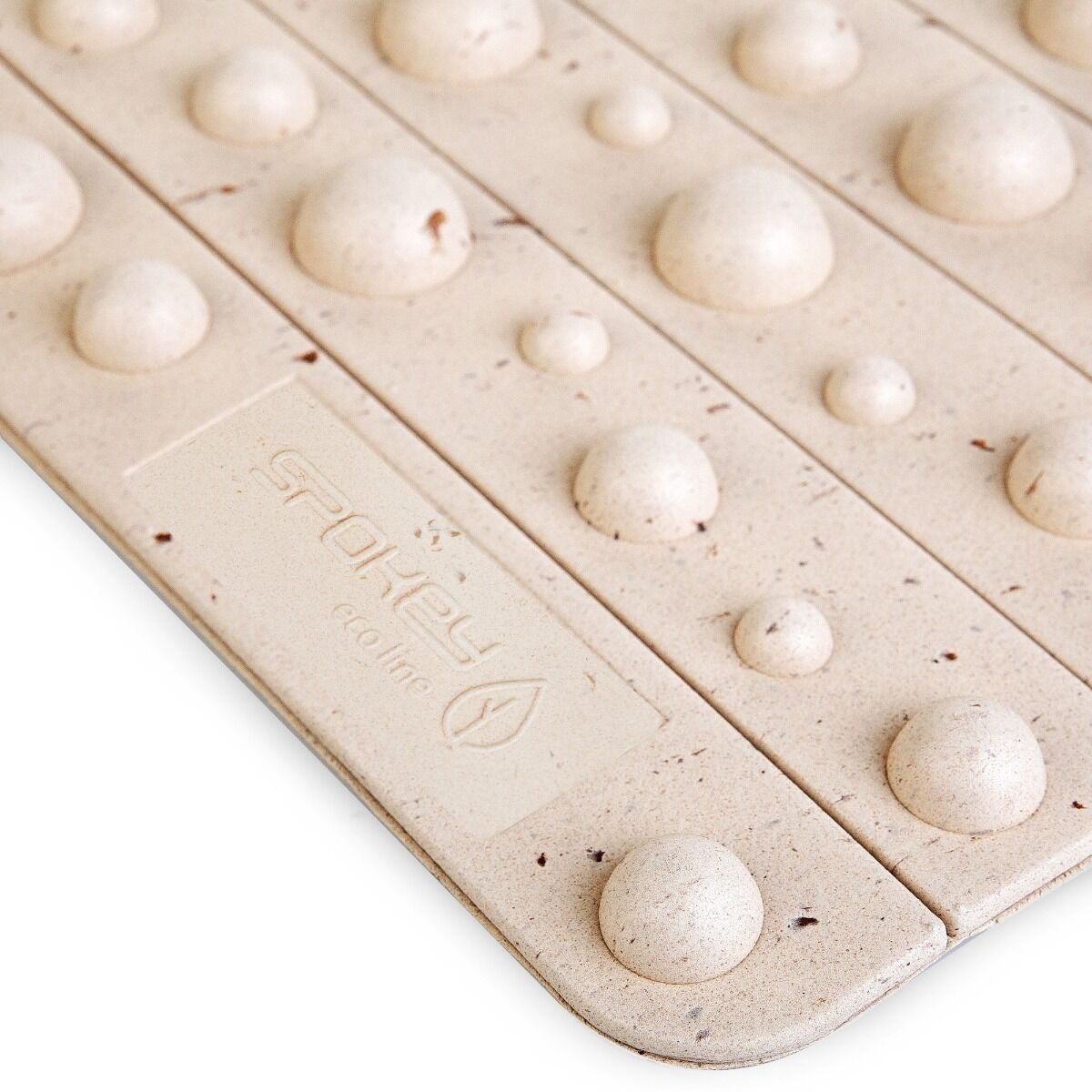 Zbliżenie beżowej maty łazienkowej z wypukłymi, zaokrąglonymi wypustkami. Mata ma kształt prostokątny i logo marki.