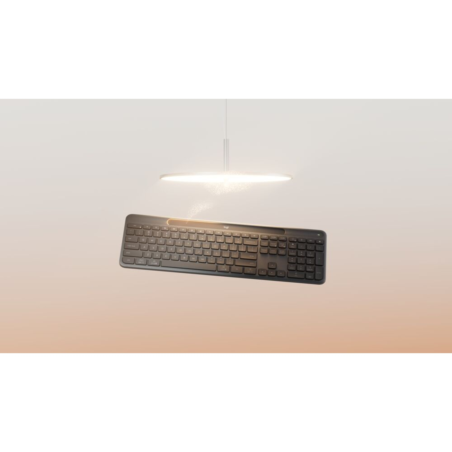 Una tastiera nera fluttua sotto un apparecchio di illuminazione circolare su uno sfondo sfumato arancione e bianco.