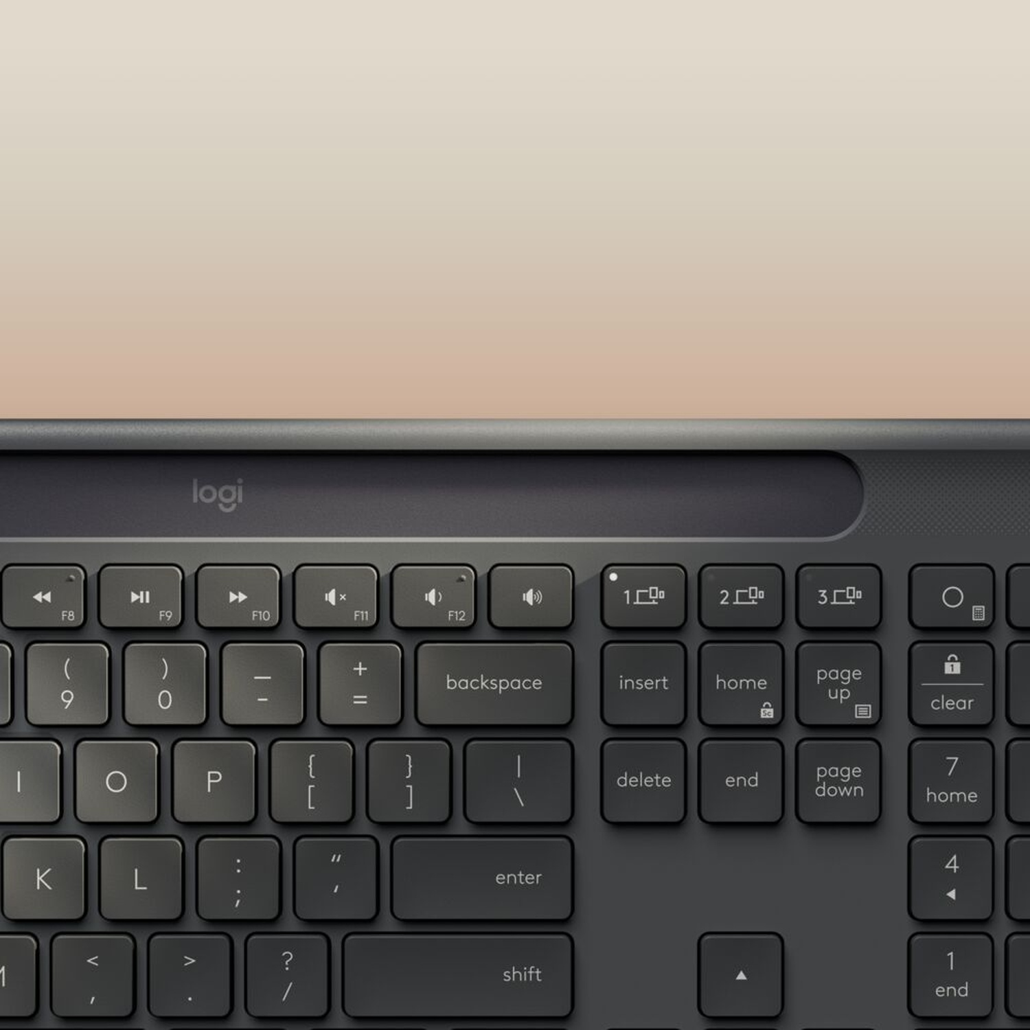 Primo piano di una tastiera Logitech grigio scuro. I tasti sono visibili, con tasti funzione e alfanumerici. Lo sfondo è sfocato.