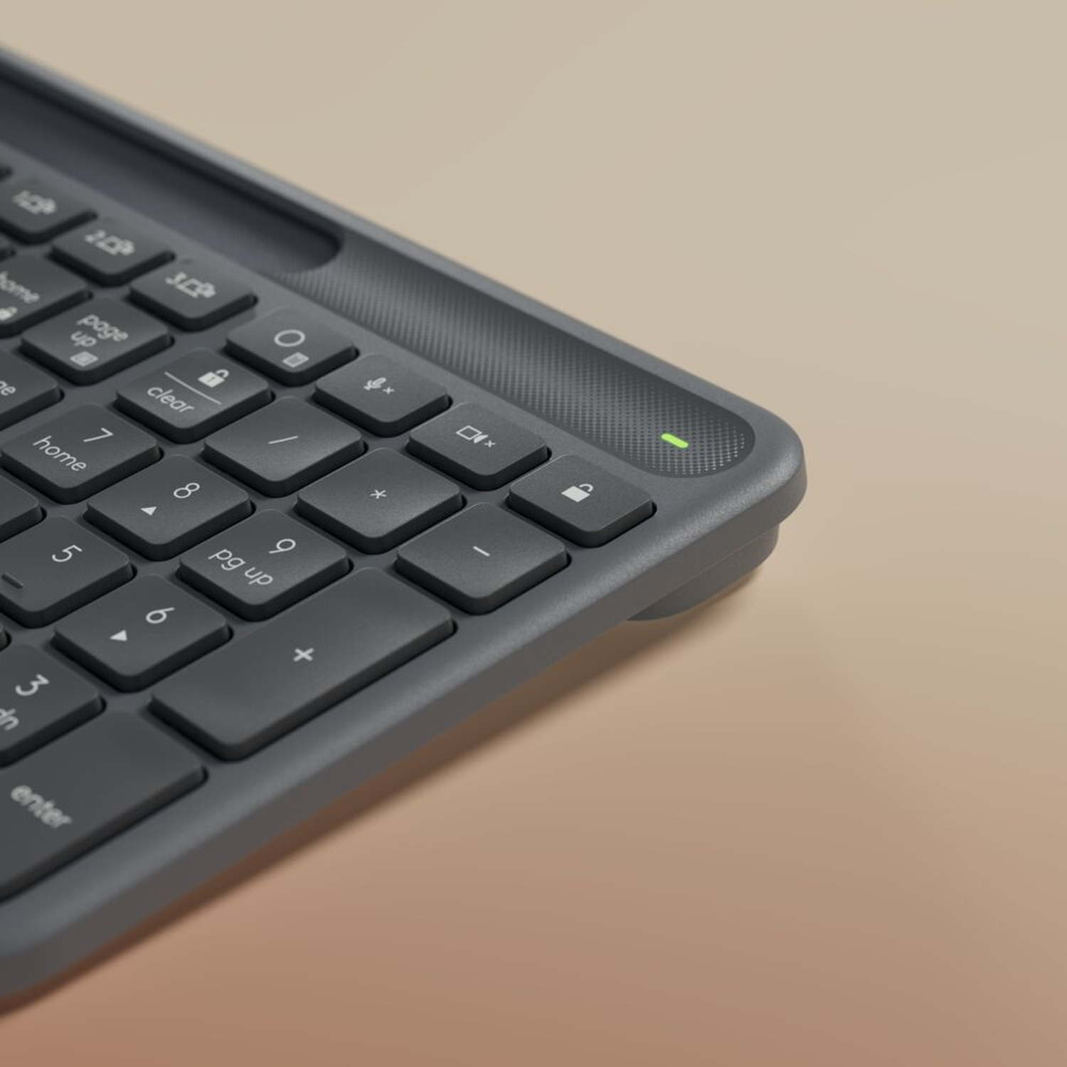 Primo piano di una tastiera grigio scuro con lettere bianche. Alcuni tasti etichettati 'clear', 'home' e numeri. Luce verde accesa.