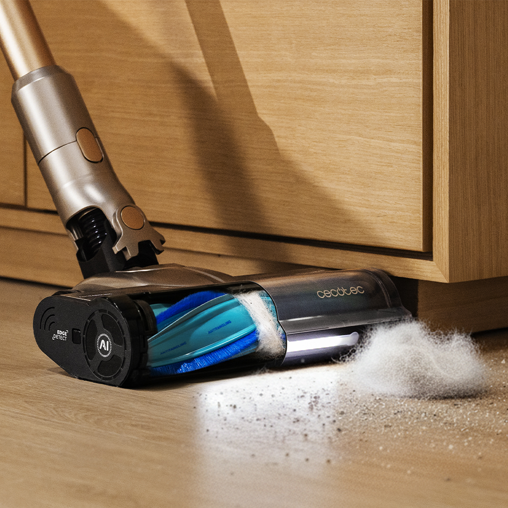 Una aspiradora inalámbrica limpia un piso de madera, recogiendo polvo y escombros. La aspiradora está cerca de un armario de madera.