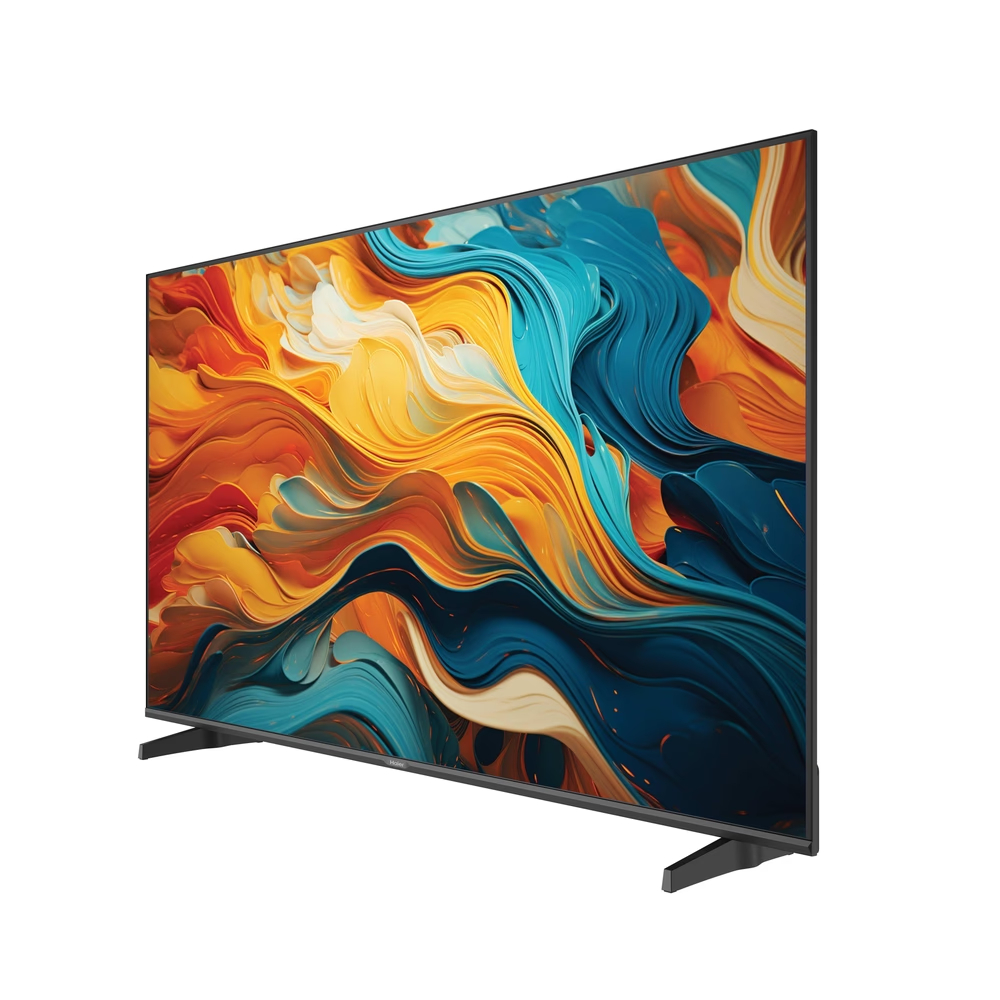 Un televisor grande muestra arte abstracto en naranja, amarillo y azul. El televisor tiene un marco negro y está sobre soportes negros, sobre blanco.