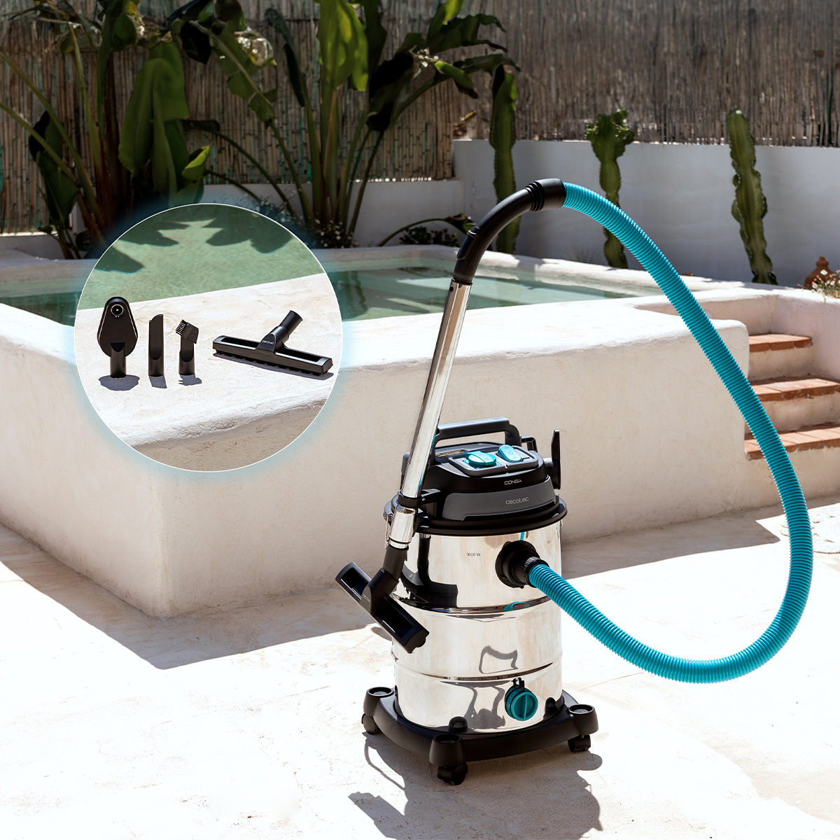 Una aspiradora de acero inoxidable con una manguera azul. Accesorios en un círculo. Fondo: piscina, plantas y escalones.