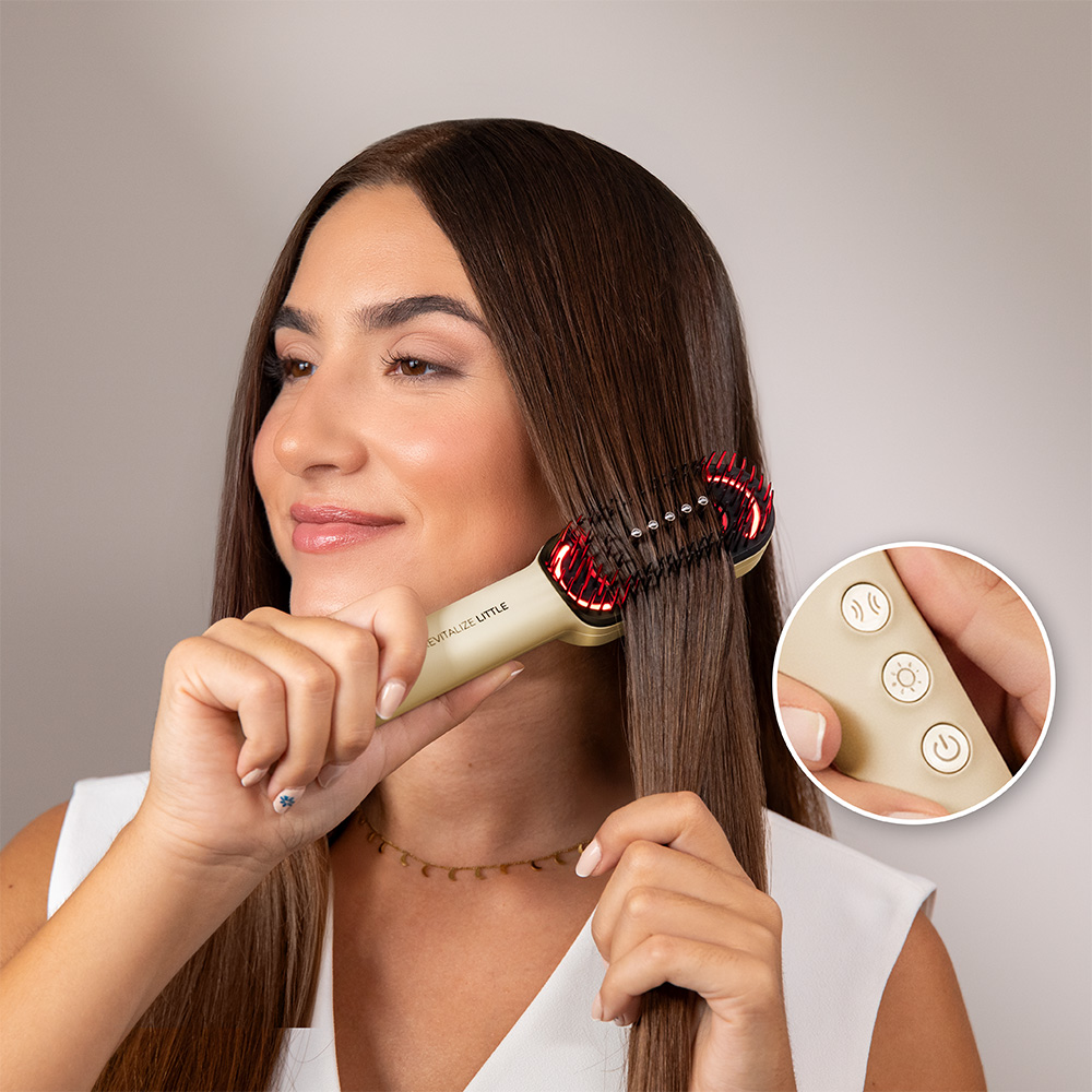 Una mujer se cepilla el cabello castaño con un cepillo Revitalize Little. Un primer plano muestra los botones del cepillo. Lleva un collar.