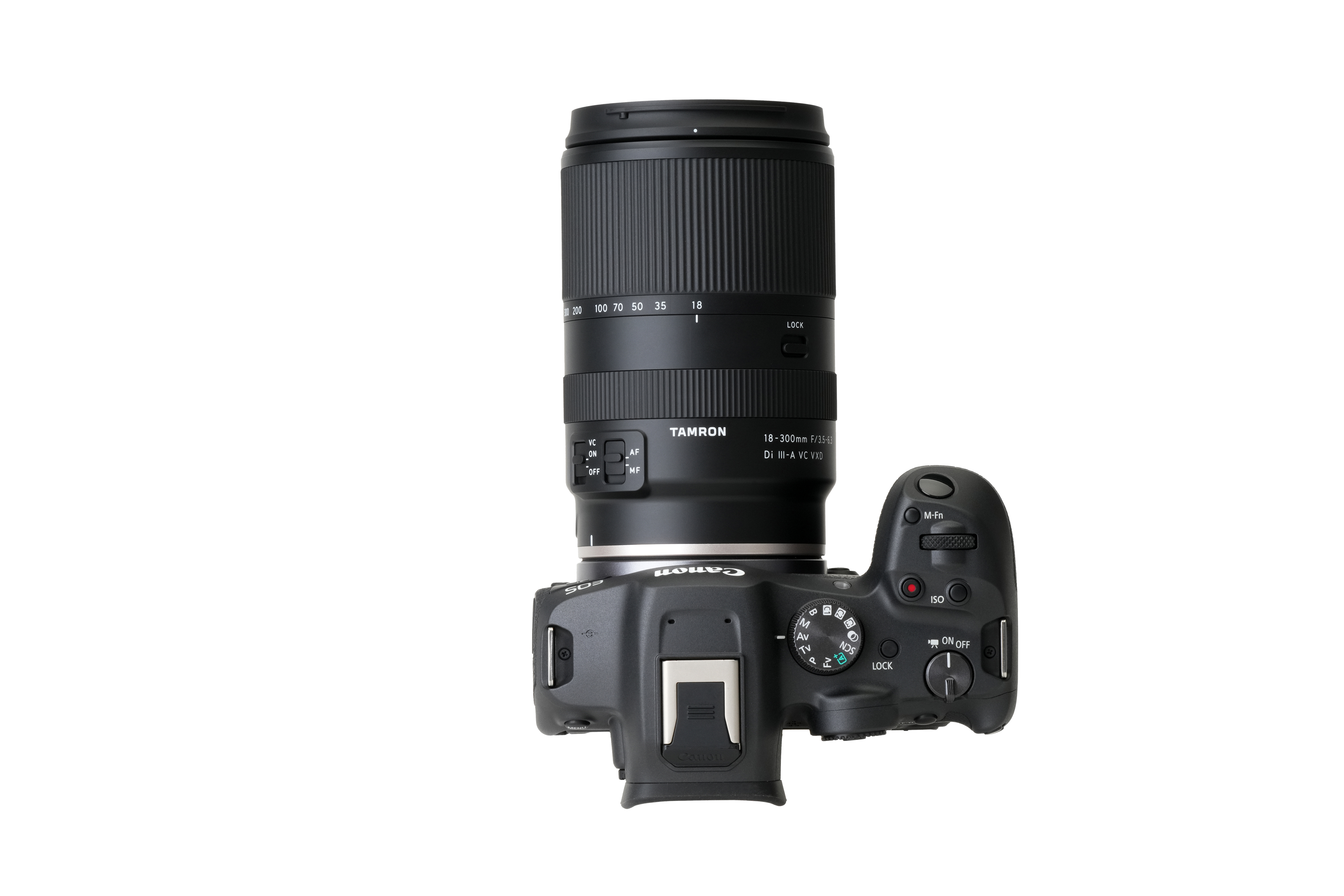 Draufsicht auf eine Canon-Kamera mit einem Tamron-Objektiv. Die Kamera ist schwarz, auf weißem Grund. Das Objektiv hat Zahlen.