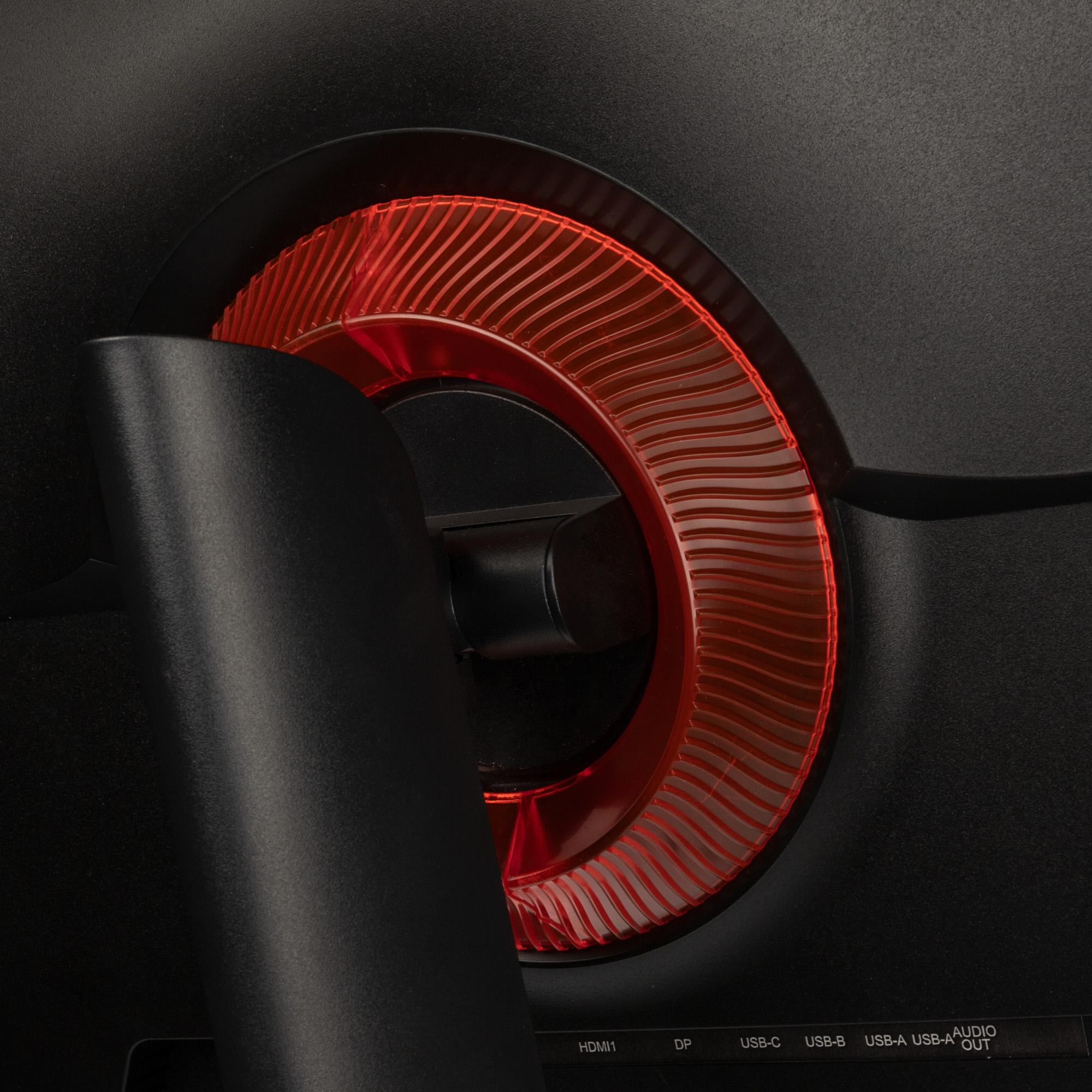 Nahaufnahme der Rückseite eines schwarzen Computermonitors. Rotes, halbkreisförmiges Designelement. HDMI-, DP- und USB-Anschlüsse sind sichtbar.
