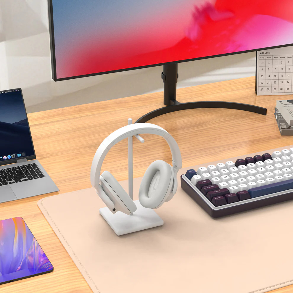 Konfiguracja biurka z monitorem, słuchawkami, klawiaturą, laptopem i tabletem. Tło zawiera kalendarz.