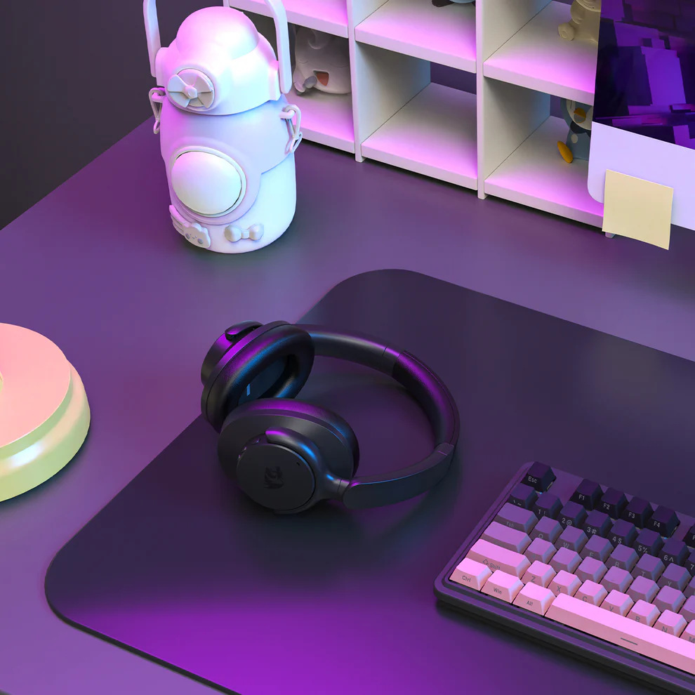 Konfiguracja biurka ze słuchawkami, klawiaturą, butelką wody i figurkami. Konfiguracja jest oświetlona fioletowymi i białymi światłami.