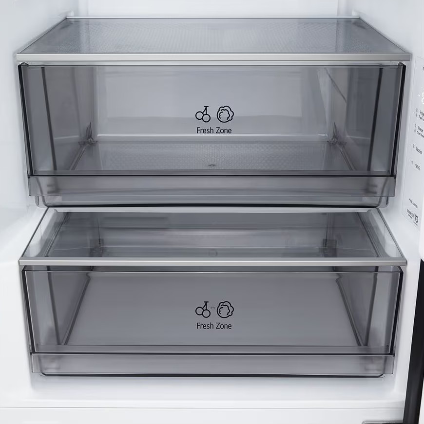 Wewnątrz lodówki widać dwie przezroczyste szuflady z napisem 'Fresh Zone'. Górna szuflada znajduje się nad dolną.
