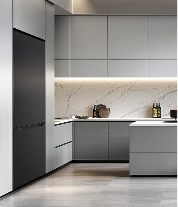 Nowoczesna kuchnia z szarymi szafkami, czarną lodówką, marmurowym blatem. Zawiera butelki, miskę i czarny garnek.