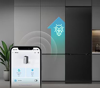 Smartfon pokazuje aplikację lodówki. Żarówka z liśćmi nad lodówką wskazuje na efektywność energetyczną.