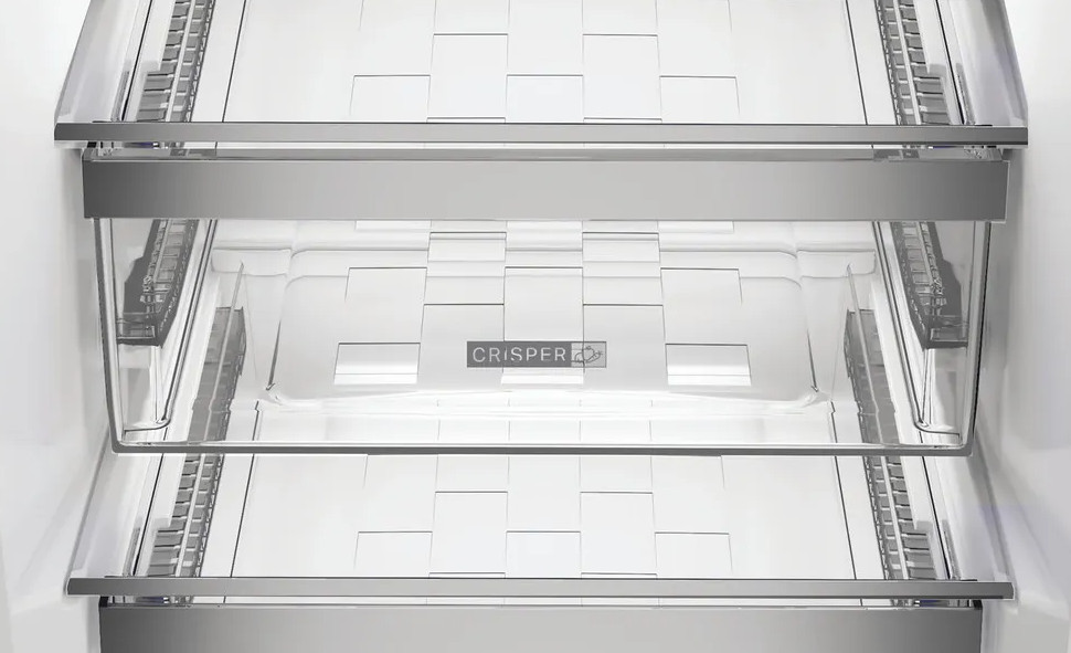 Wewnątrz lodówki widoczne są trzy przezroczyste, plastikowe półki. Słowo "CRISPER" jest wydrukowane na środku dolnej półki.