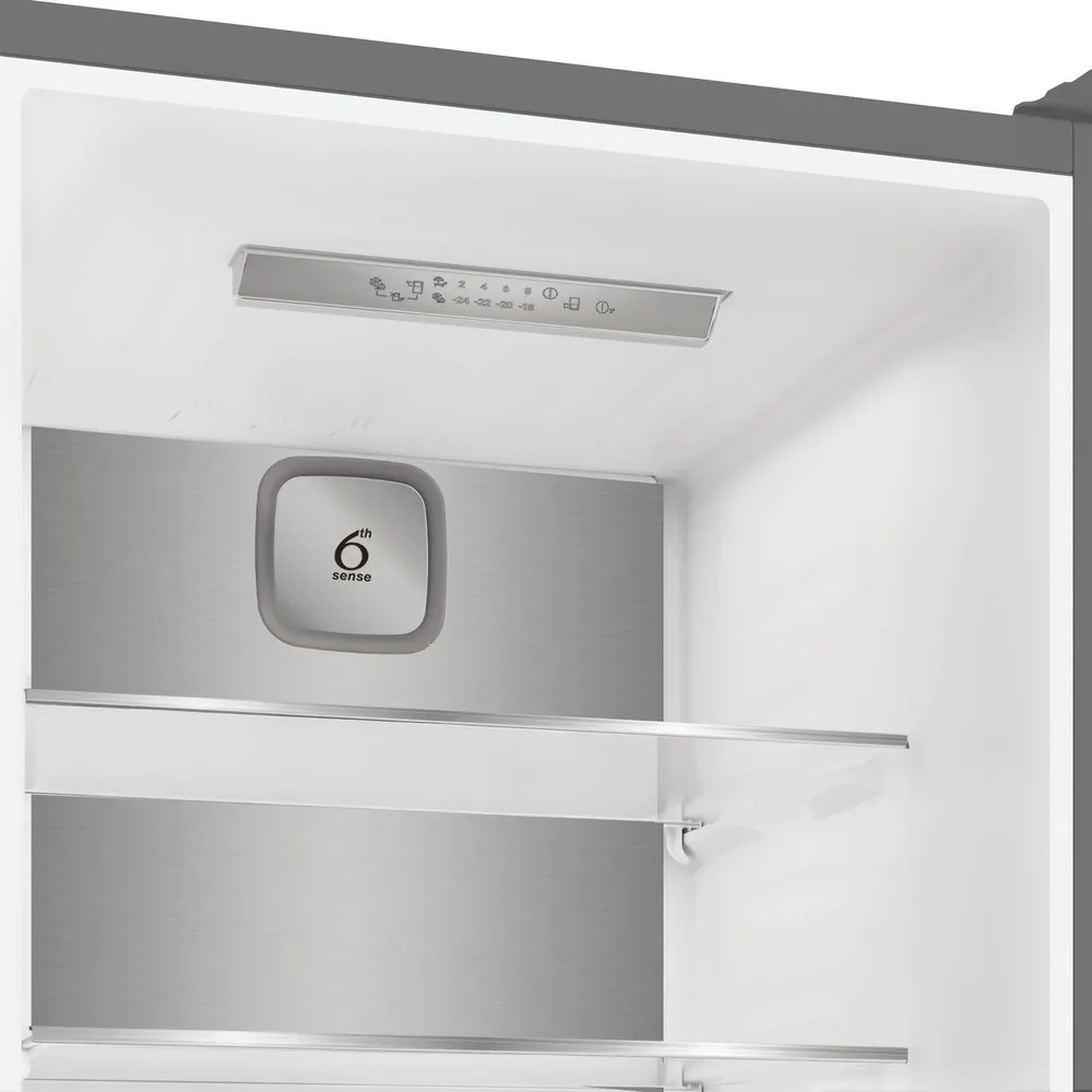 Wnętrze lodówki. Ma półki, regulatory temperatury i przycisk '6th sense'. Wnętrze jest białe i metaliczne.