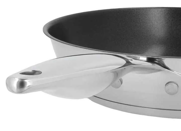 Zbliżenie patelni ze stali nierdzewnej z czarnym wnętrzem i uchwytem z otworem.