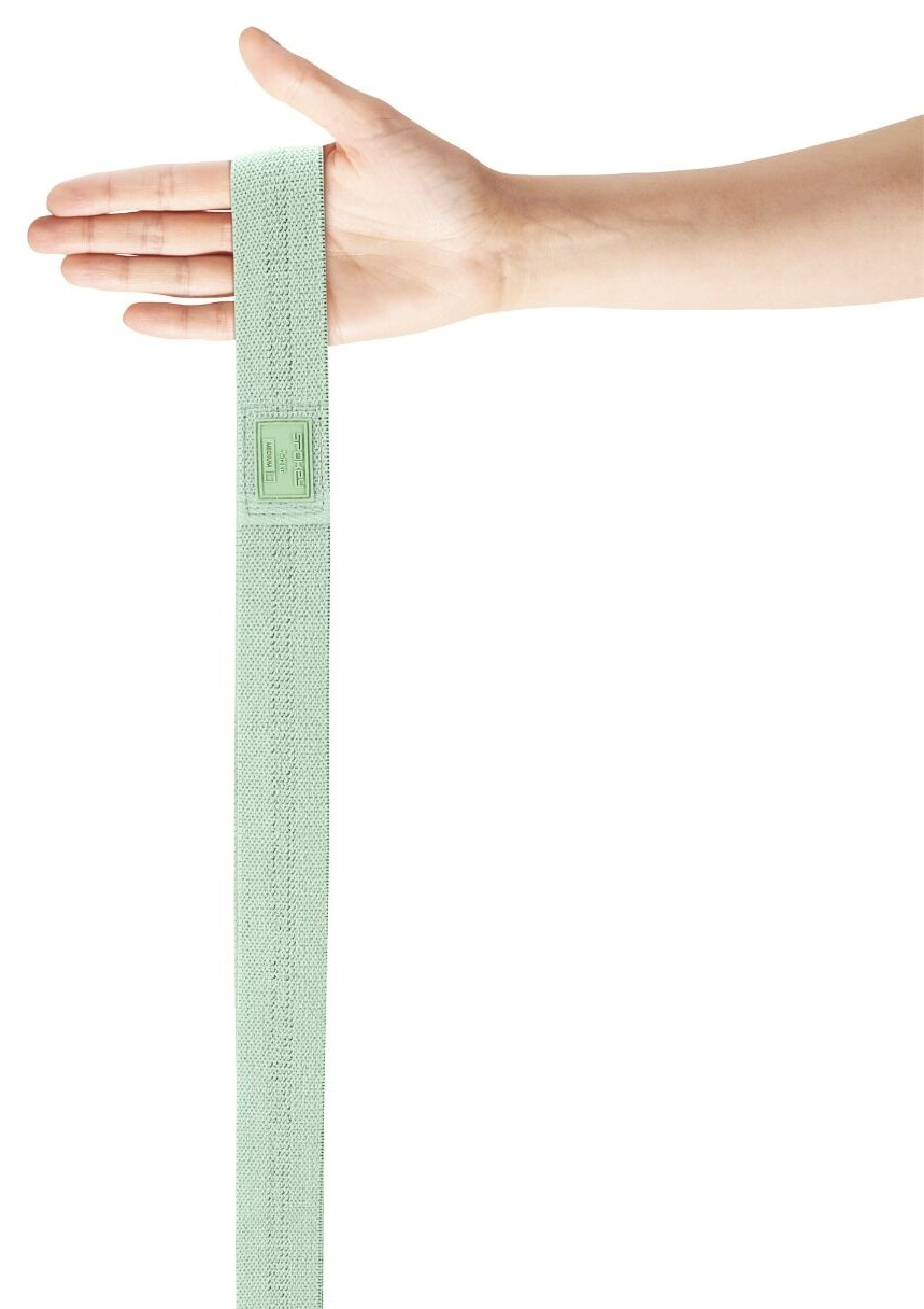 Ręka trzyma jasnozieloną taśmę oporu. Taśma jest pionowa, z etykietą blisko dłoni. Białe tło.