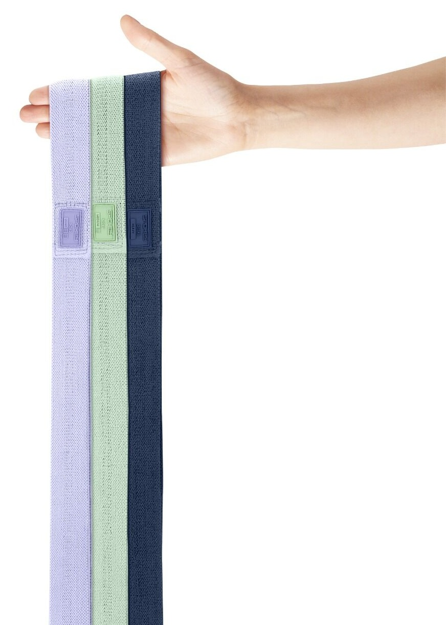 Dłoń trzyma trzy gumy oporowe: fioletową, zieloną i niebieską. Każda guma ma etykietę. Białe tło.