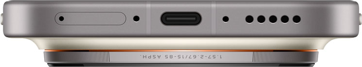 Nahaufnahme der Unterkante eines Telefons. Es hat einen USB-C-Anschluss, Lautsprecherlöcher und ein Kameramodul mit Text 1.57-2.67/15-85 ASPH.