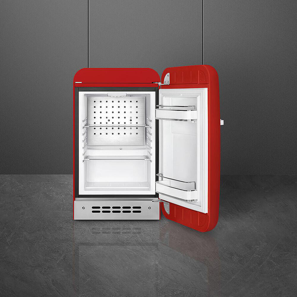 Ein roter Kühlschrank mit offener Tür. Innen weiß mit Regalen. Der Hintergrund ist eine dunkelgraue Wand und Boden.