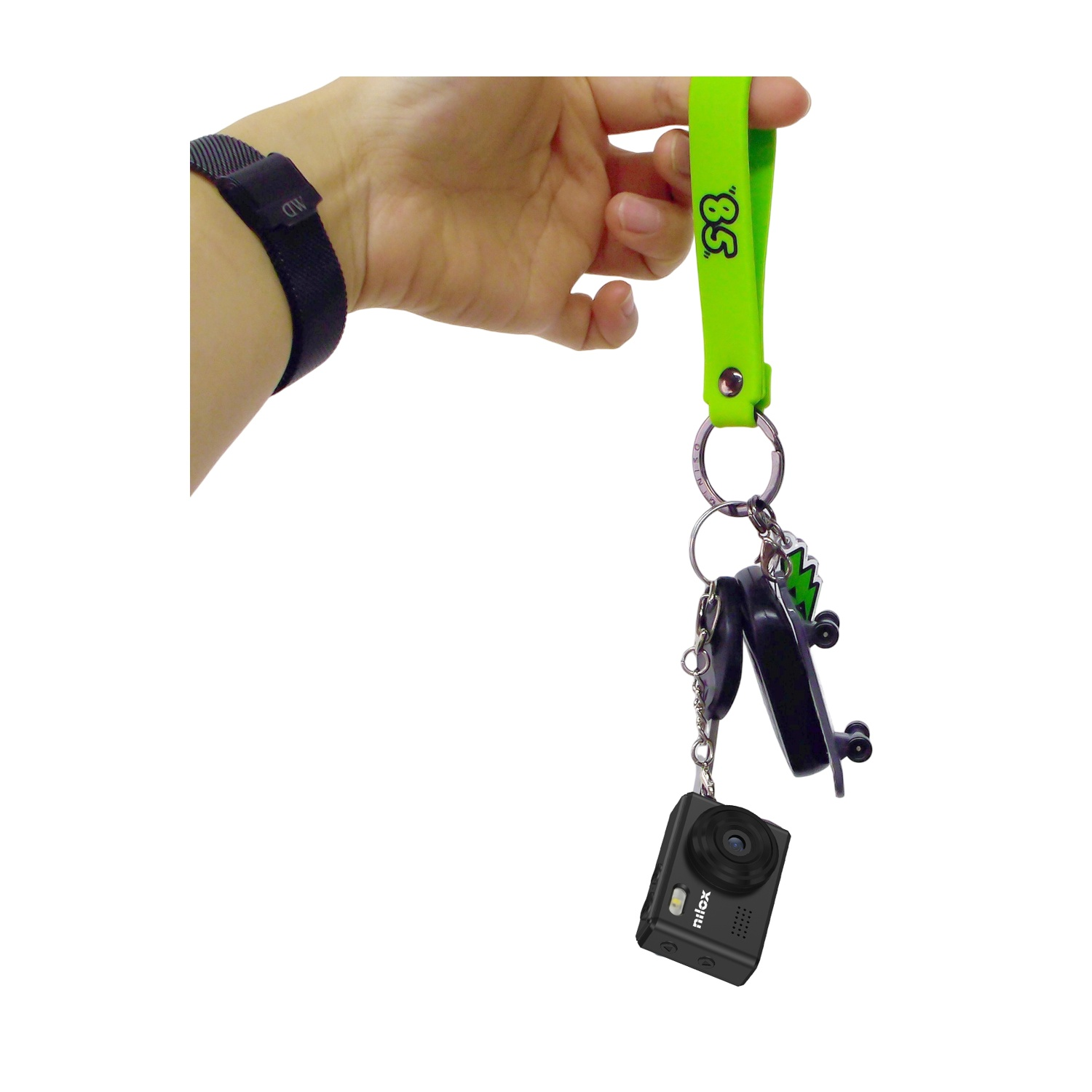 Una mano tiene un cordino verde con chiavi e una piccola fotocamera. Un orologio è indossato sul polso.