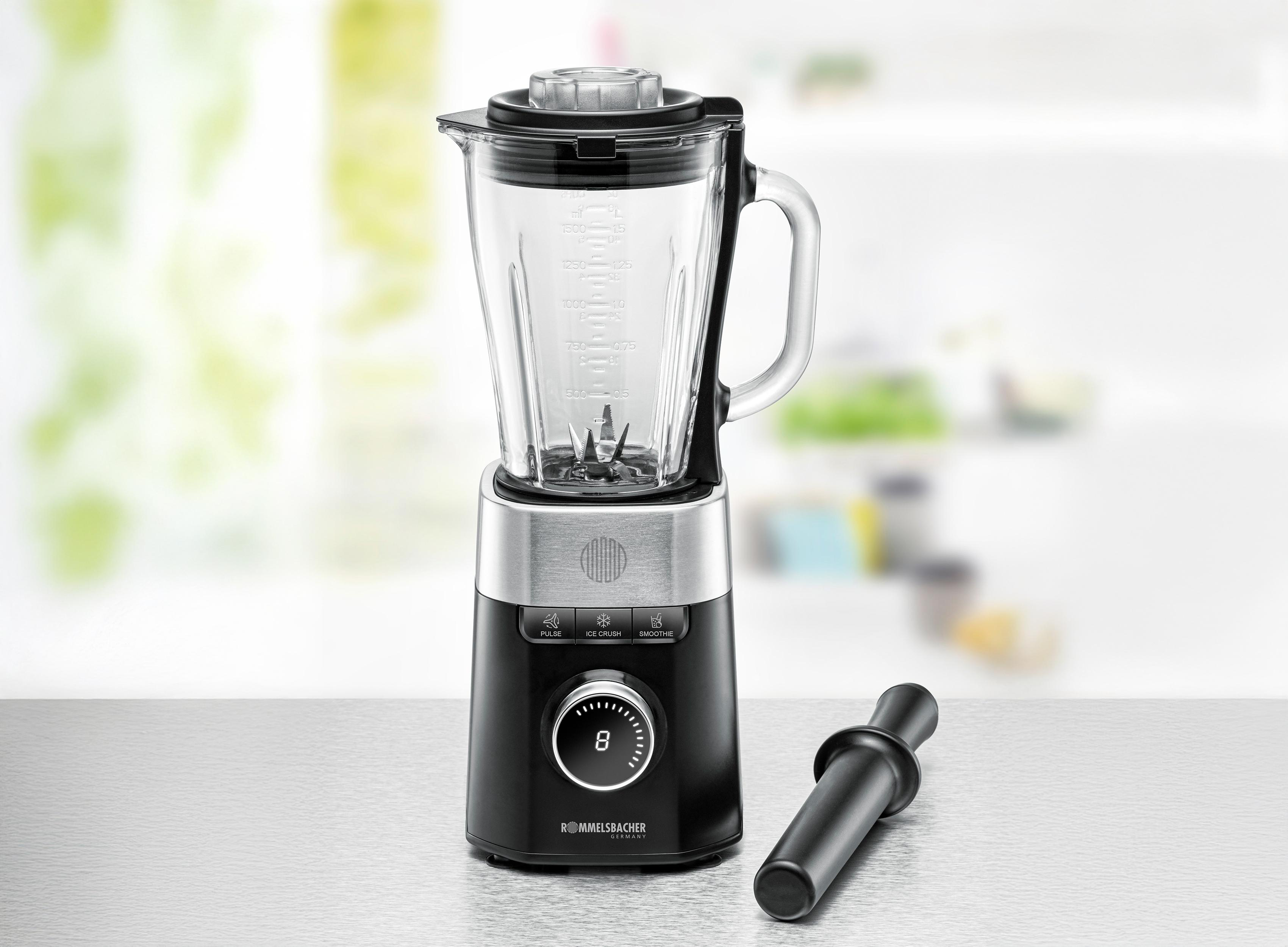 Ein Mixer mit schwarzem Sockel und Glaskrug, ein schwarzer Stopfer rechts. Der Hintergrund ist unscharf.