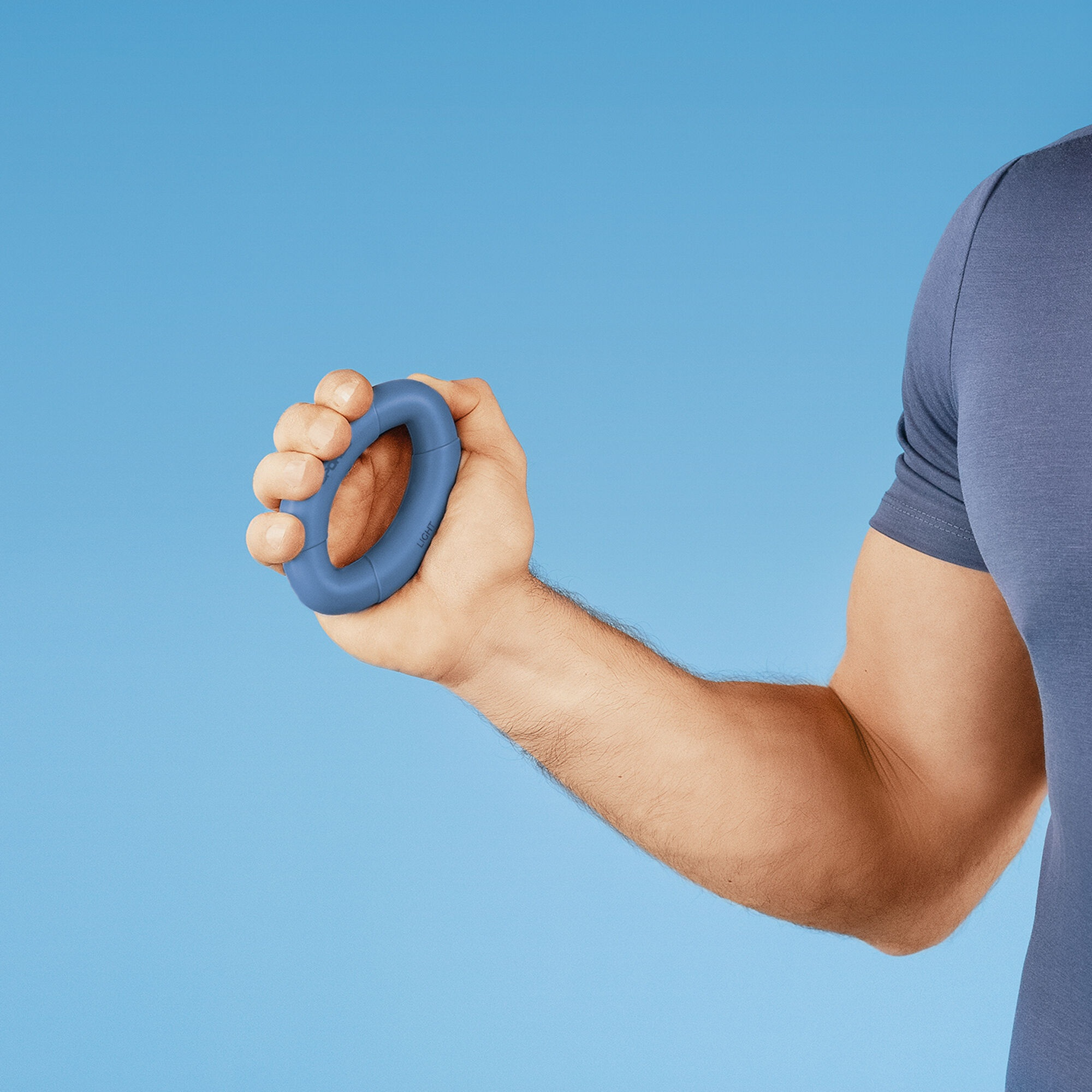 Dłoń ściska niebieski wzmacniacz chwytu. Tło to gradient niebieskiego. Widoczne ramię i ramię osoby.