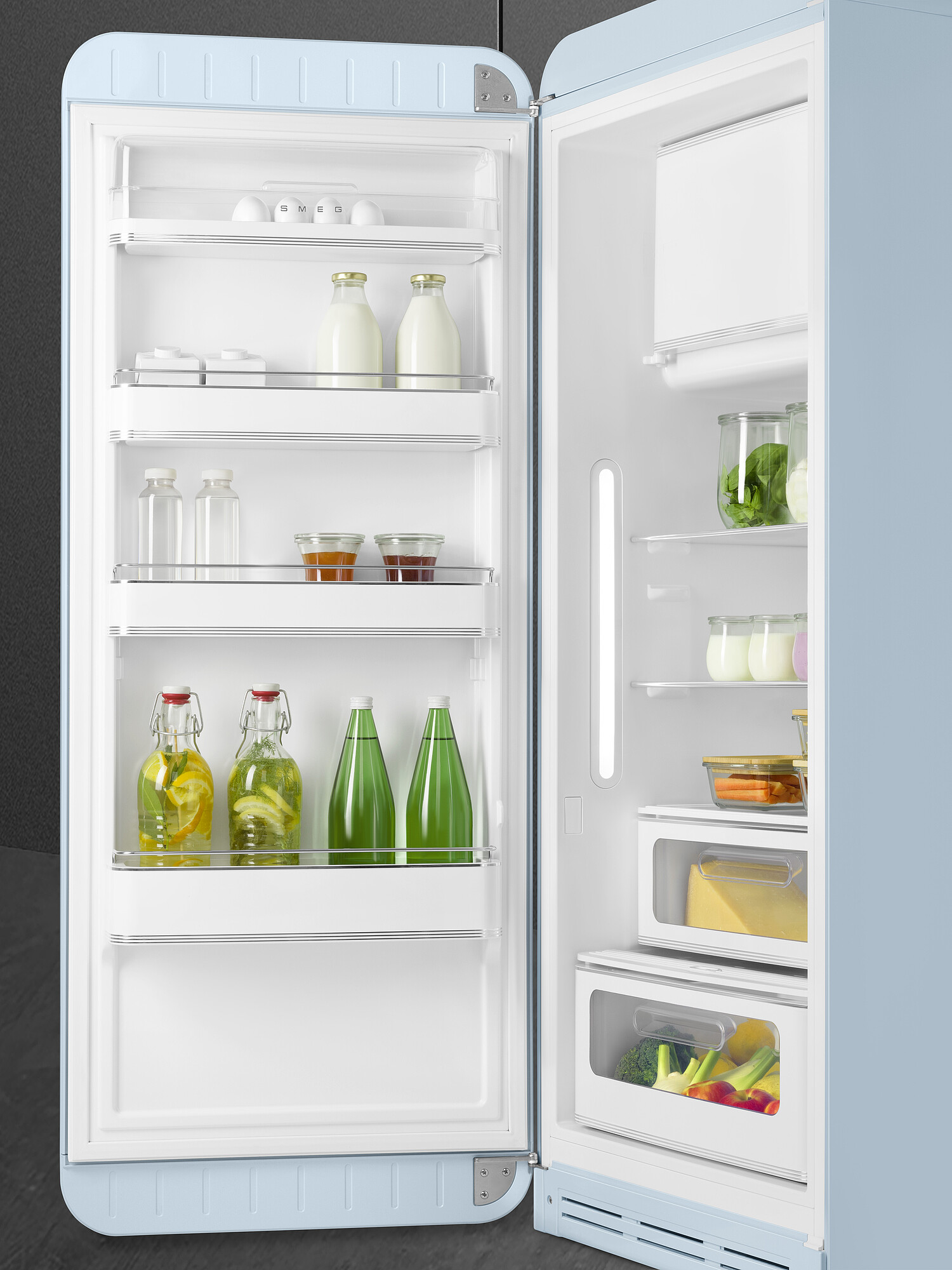 Offener hellblauer Kühlschrank mit Lebensmitteln gefüllt: Eier, Milch, Getränke und Gemüse. Die Tür ist offen.