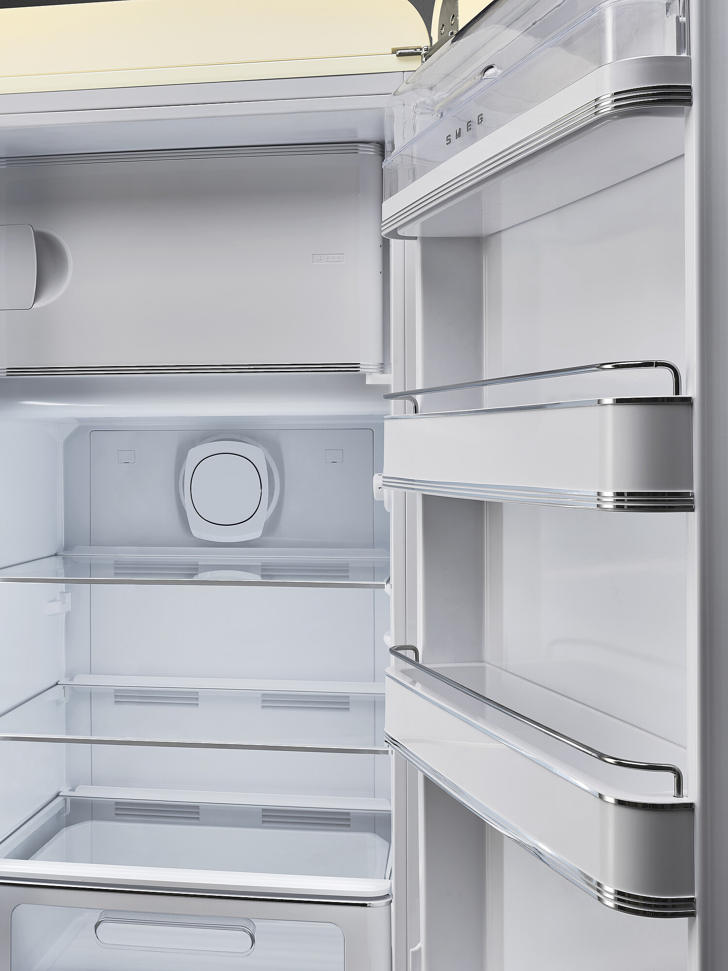 Offener weißer SMEG-Kühlschrankinnenraum. Regale und Fächer sichtbar. Silberne Akzente und transparente Kunststoffböden.