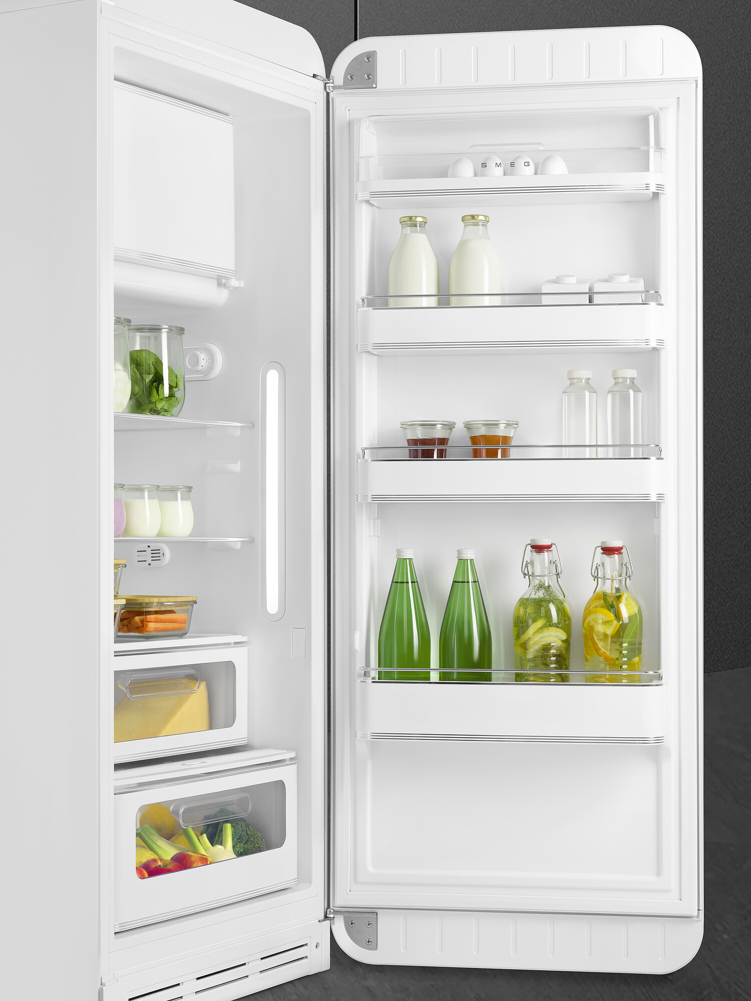 Offener weißer Kühlschrank gefüllt mit Lebensmitteln: Eier, Milchflaschen, Gemüse, Gläser mit Konserven und Wasserflaschen.