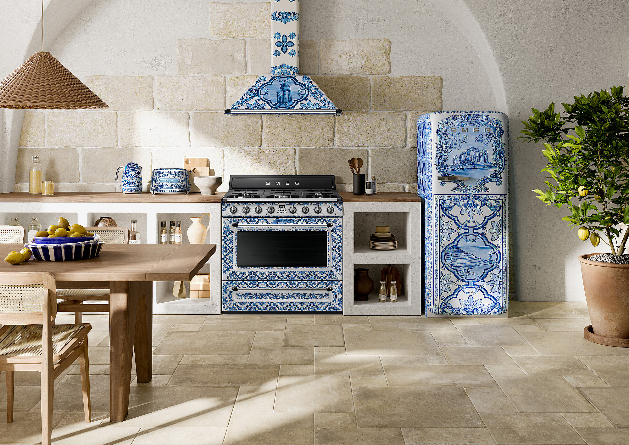 Küche mit blau-weißem Fliesendesign, Herd, Kühlschrank, Zitronen und einer Pflanze. Holztisch und Stühle. Steinmauern.