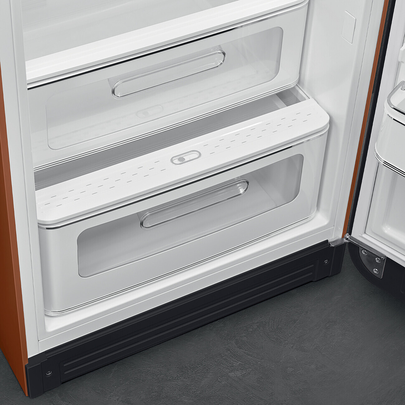 Offener Kühlschrank mit zwei transparenten Schubladen. Oranger Rahmen, weißer Innenraum und eine dunkelgraue Basis auf grauem Boden.