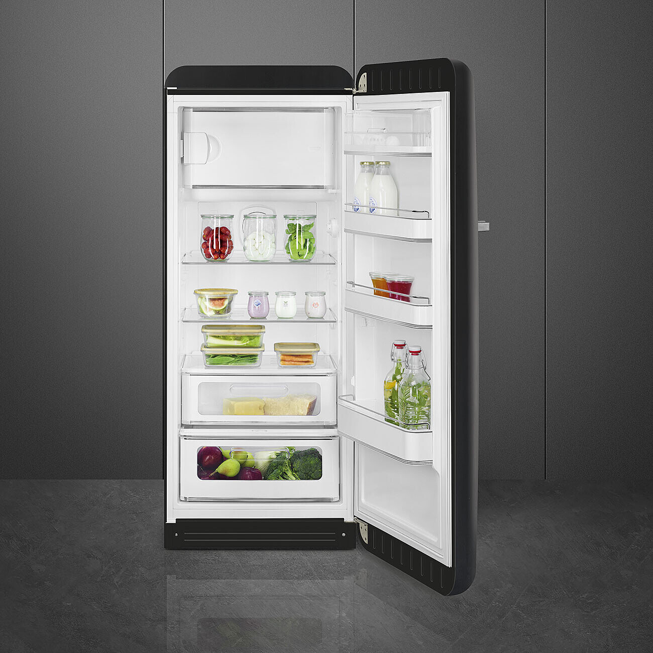Offener schwarzer Kühlschrank gefüllt mit Obst, Gemüse und Getränken. Gläser, Behälter und Flaschen sind auf den Regalen sichtbar.