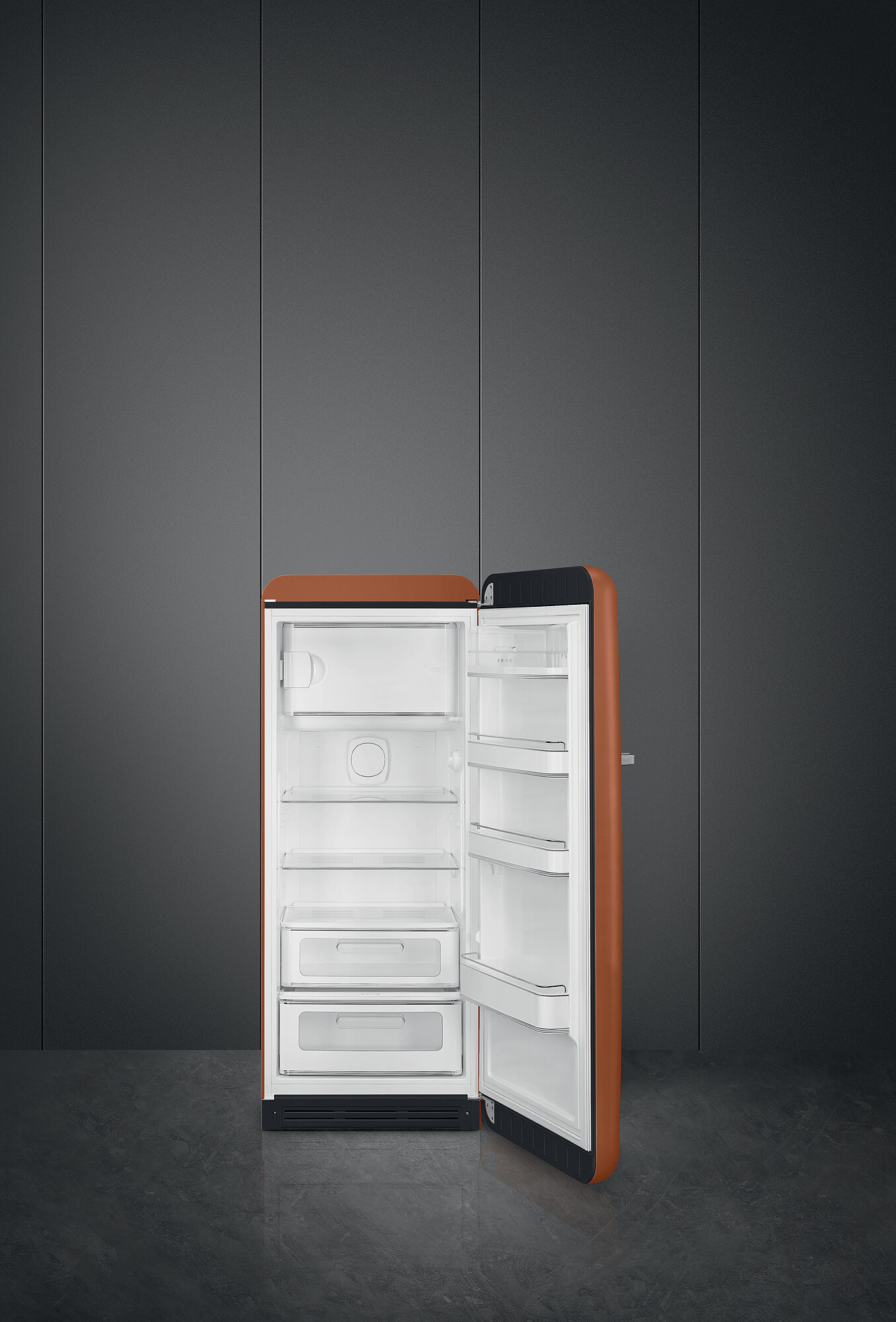 Offener brauner Kühlschrank vor grauer Wand. Der Kühlschrank ist geöffnet und zeigt Regale und Schubladen. Der Boden ist dunkel.