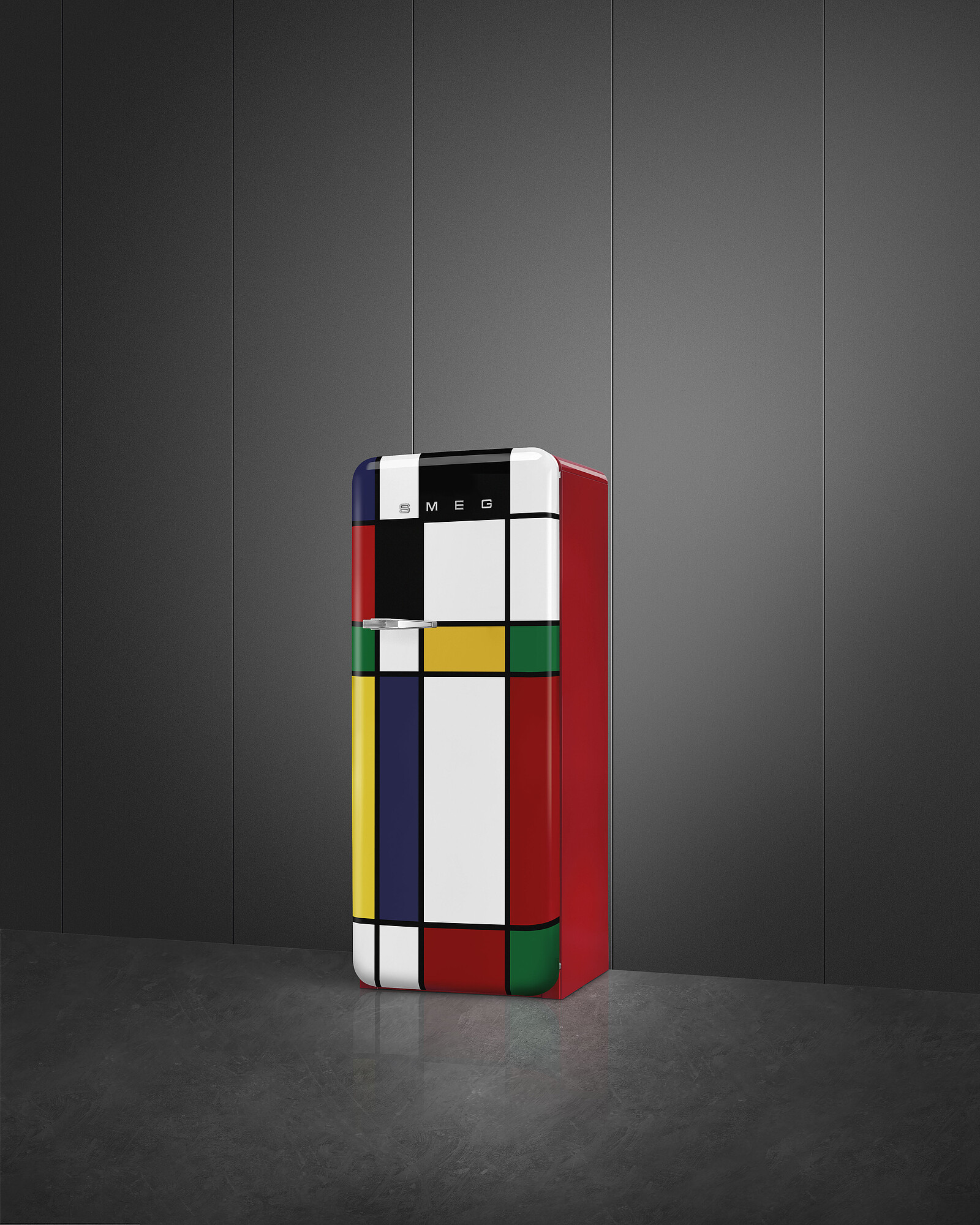 Ein farbenfroher Kühlschrank im Mondrian-Stil steht auf einem dunklen Boden vor einer grauen Wand.