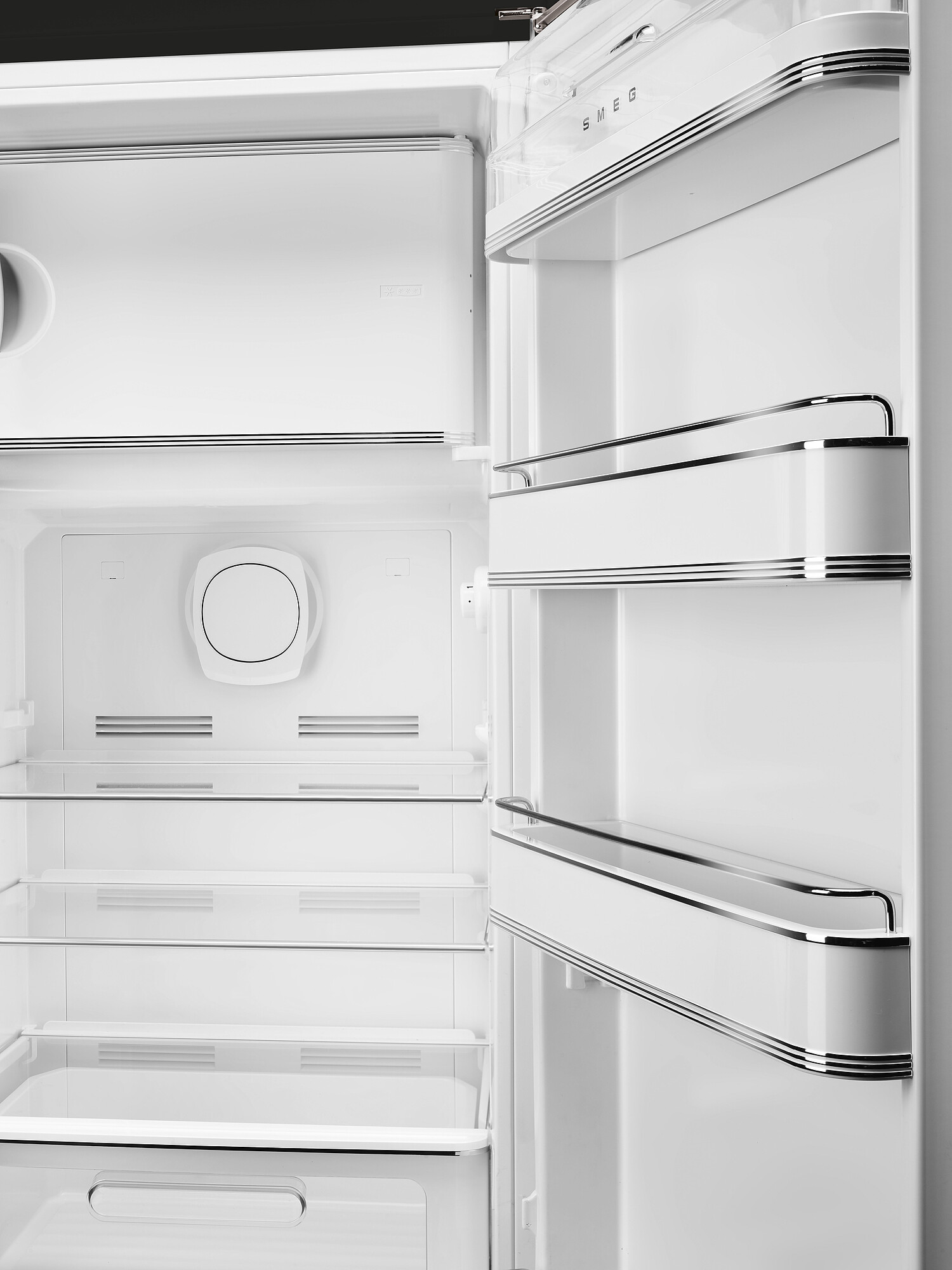 Offener weißer SMEG-Kühlschrank. Innenansicht mit Regalen, Staufächern und einem kreisförmigen Element. Chromakzente.