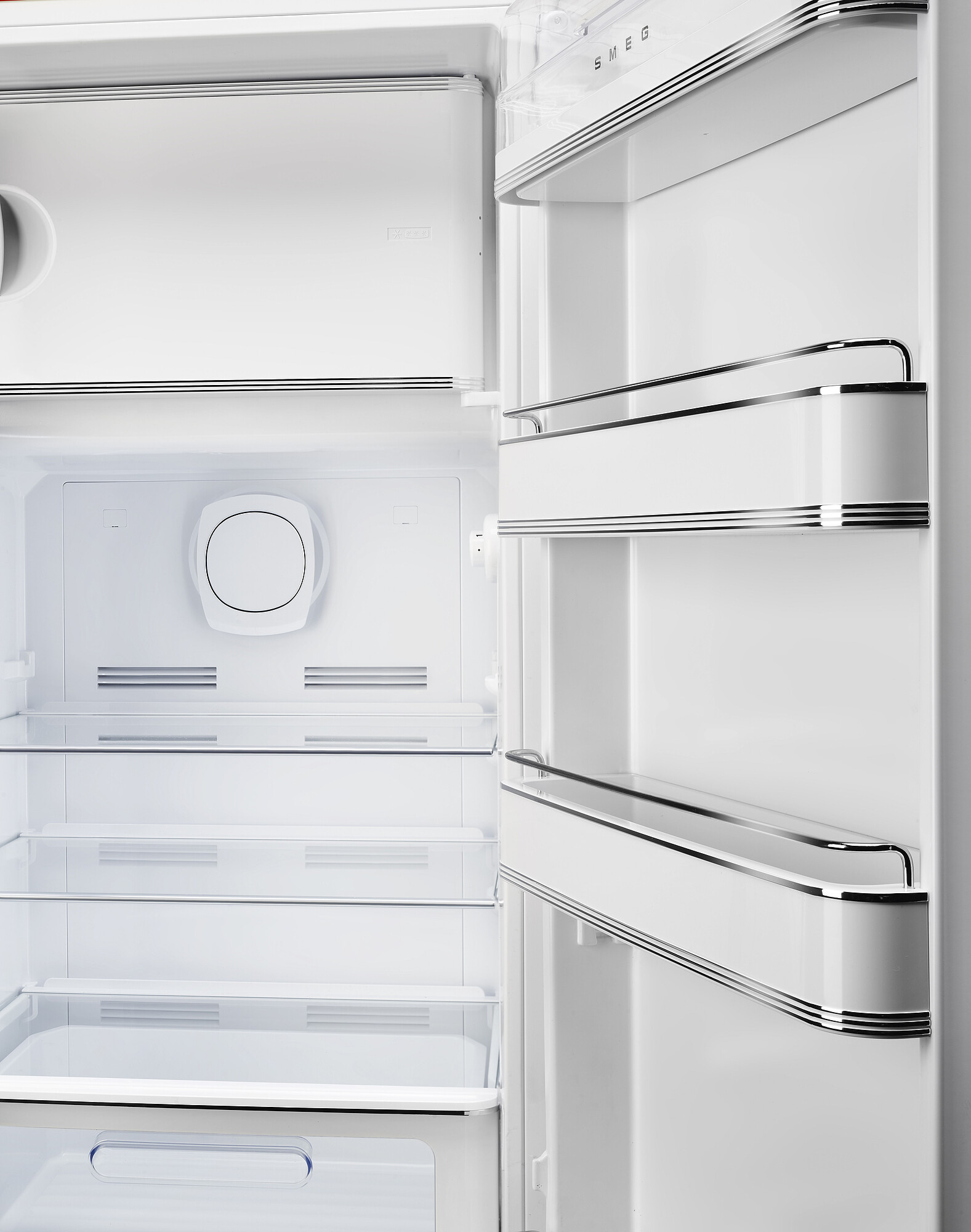 Offener weißer SMEG-Kühlschrank. Innenansicht mit Regalen, Türfächern und einem kreisförmigen Element.