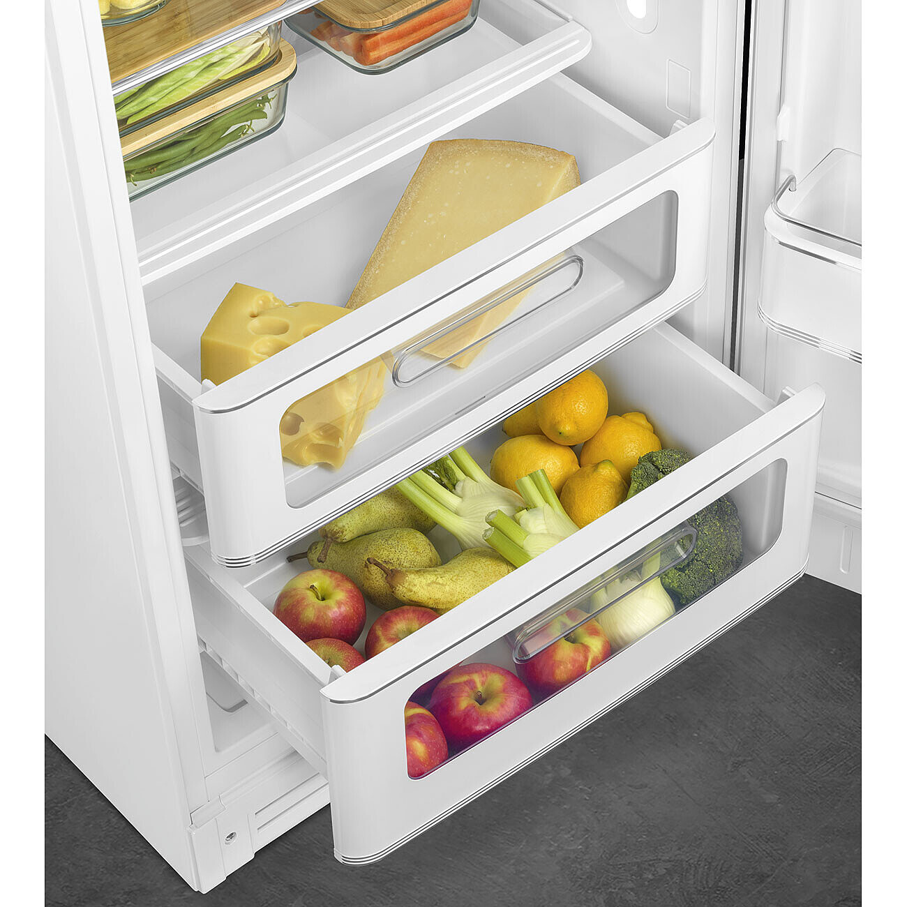 In einem Kühlschrank befinden sich in Schubladen Käse, Zitronen, Brokkoli, Äpfel, Birnen und Fenchel. Weitere Regale haben Gemüse und Karotten.