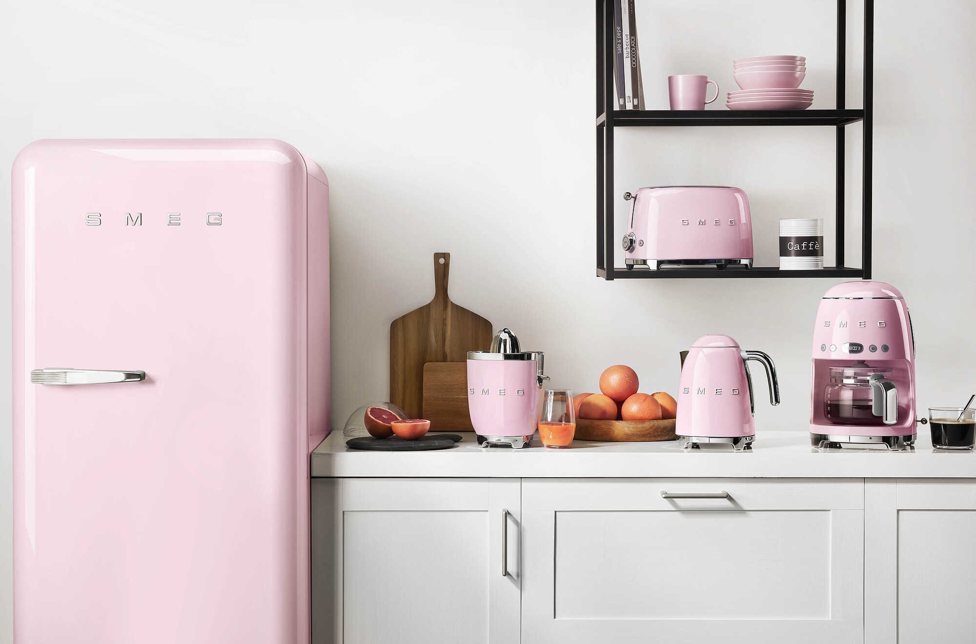 Rosa Küchengeräte und ein Kühlschrank stehen auf einer weißen Arbeitsplatte. Es gibt auch einen Toaster, einen Wasserkocher und eine Kaffeemaschine.