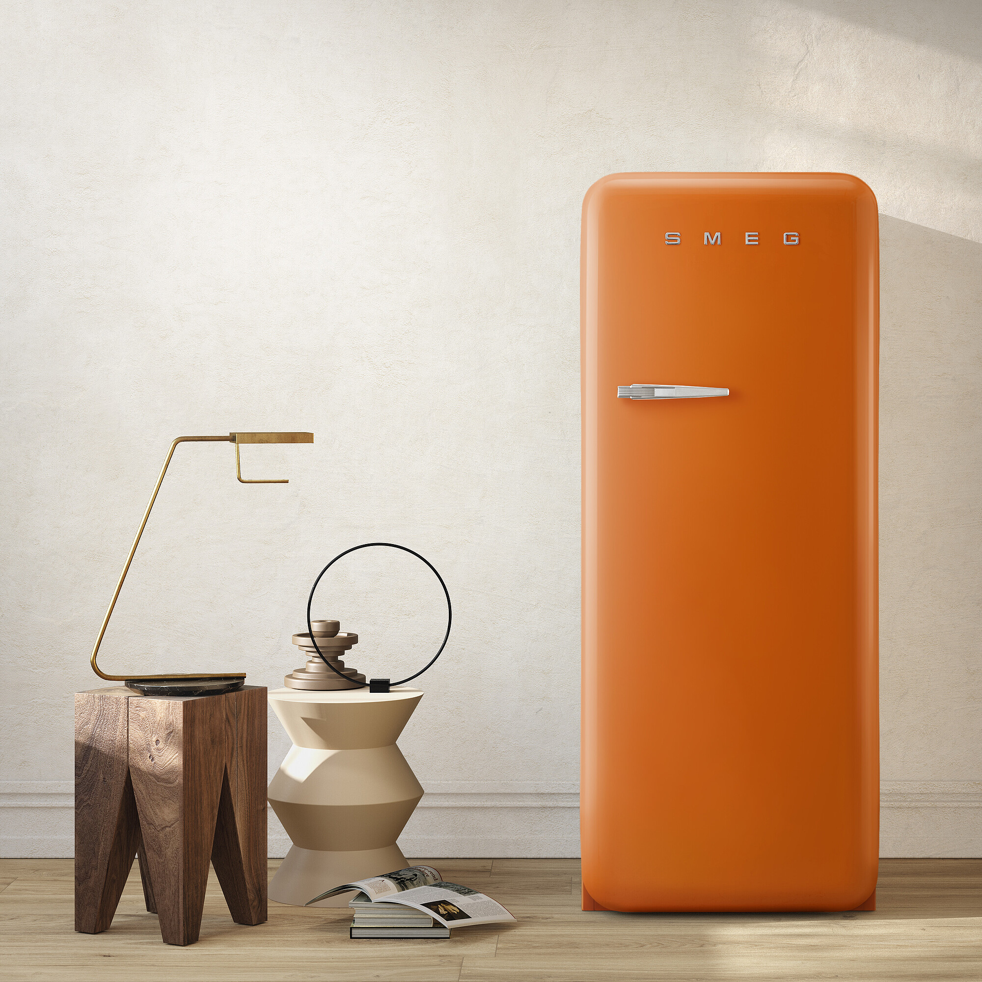 Ein orangefarbener SMEG-Kühlschrank steht neben einem Holzstuhl, einer Lampe und einem modernen Beistelltisch. Eine Zeitschrift liegt auf dem Boden.