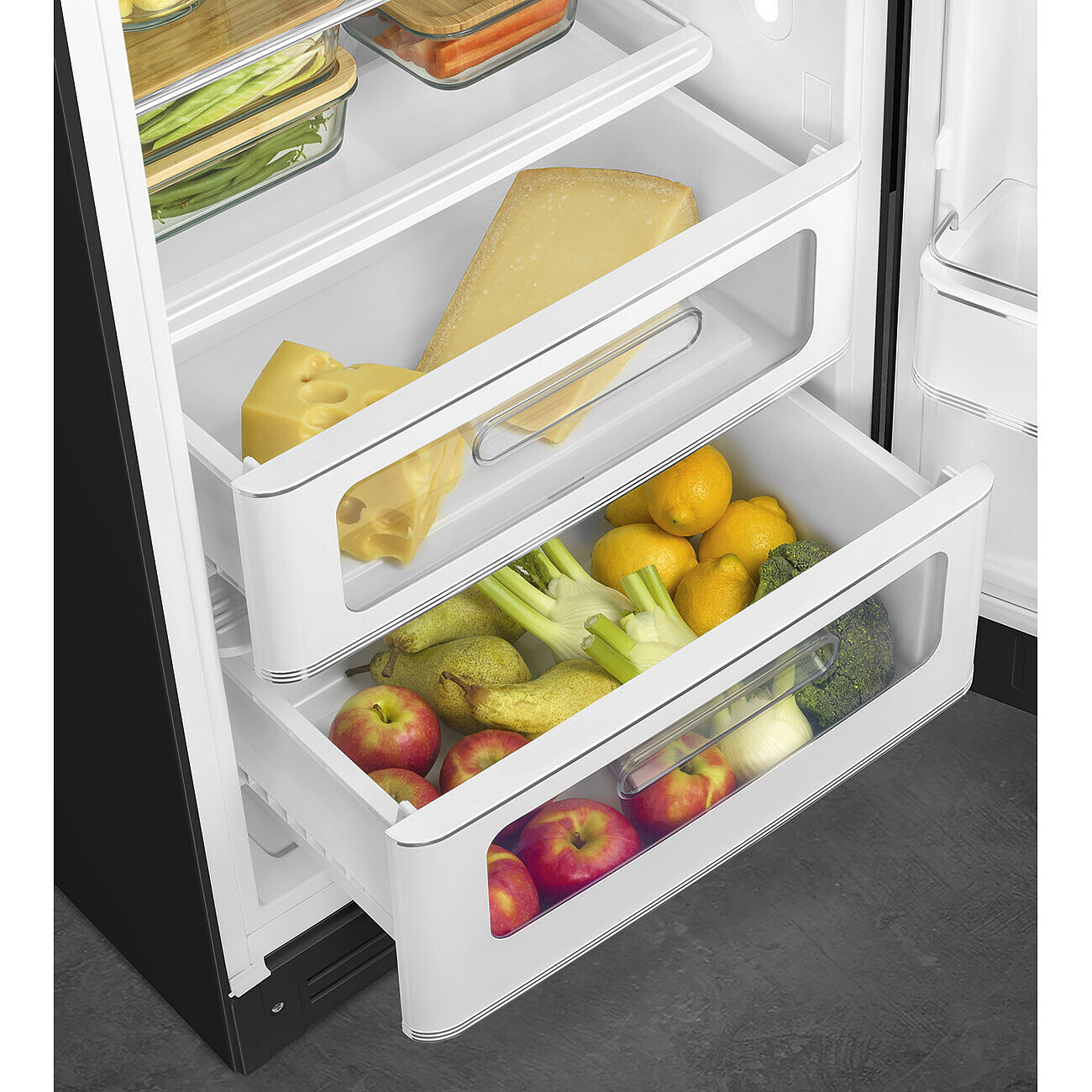 Im Kühlschrank: Schubladen mit Käse, Zitronen, Äpfeln, Birnen, Brokkoli und Fenchel. Andere Regale haben Gemüse in Glasbehältern.