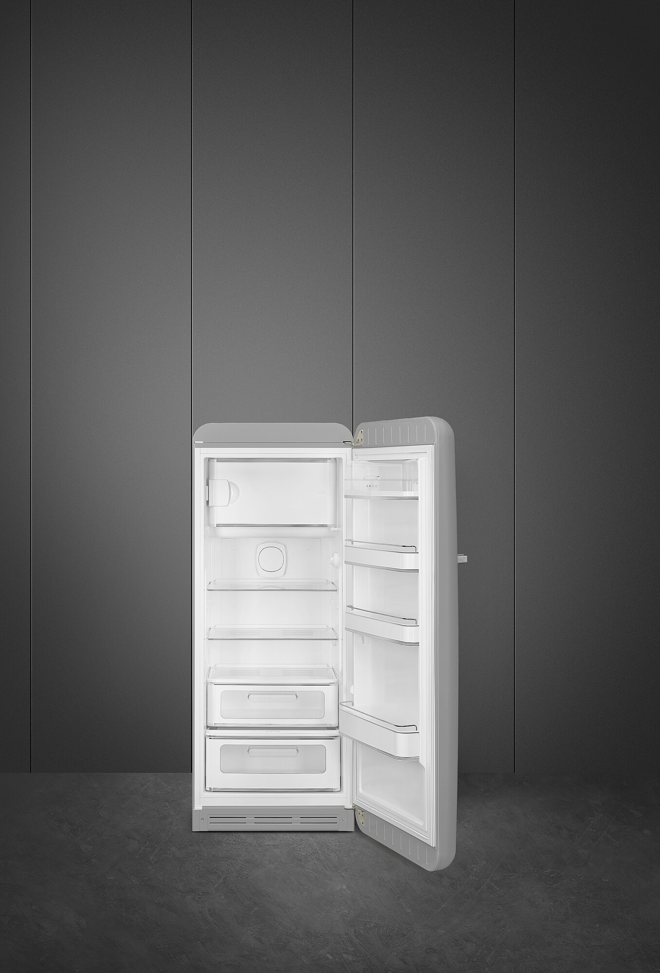 Ein grauer Kühlschrank mit geöffneter Tür, der weiße Regale zeigt. Der Hintergrund ist eine dunkelgraue Wand und Boden.