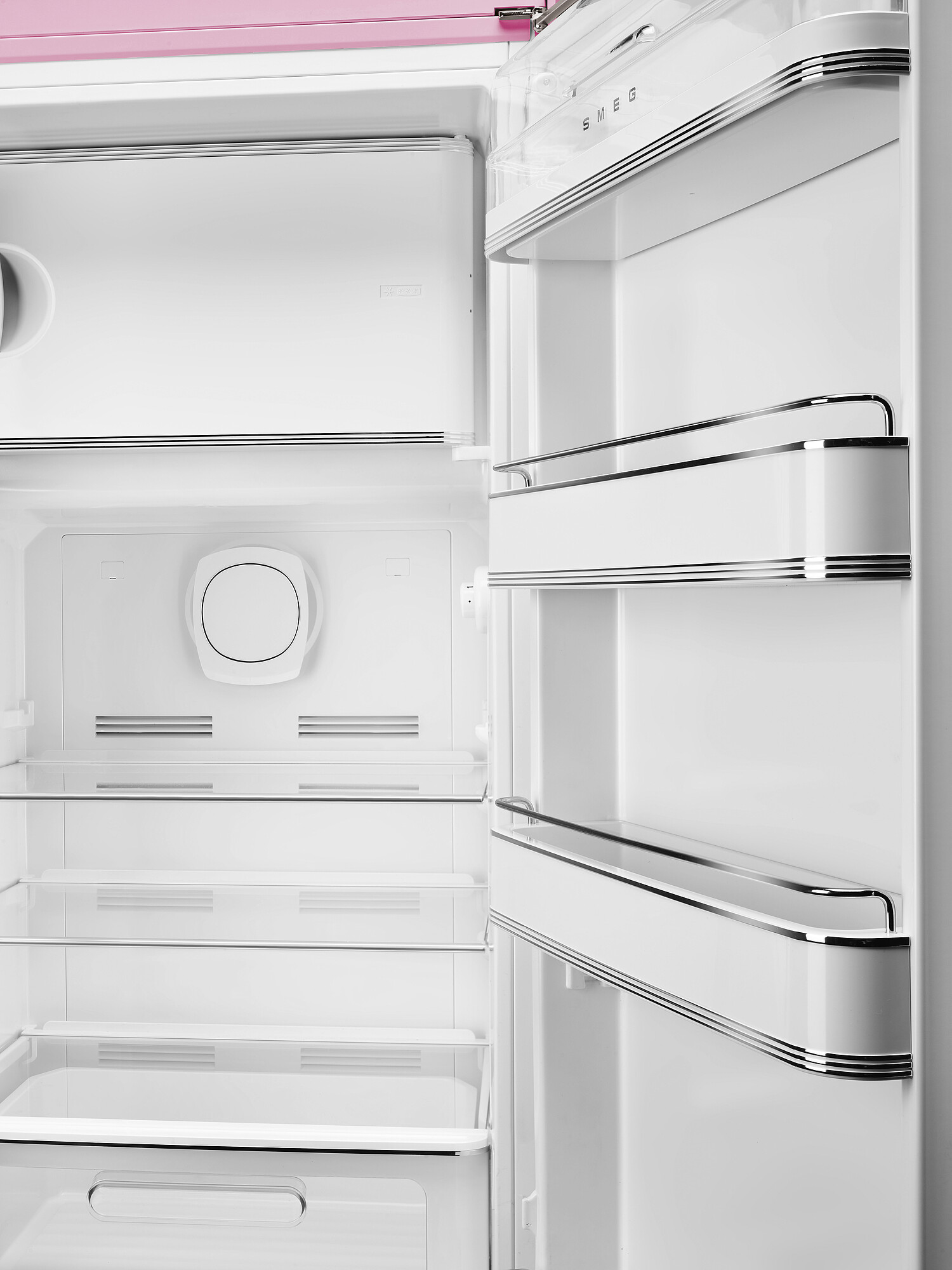 Offener weißer Kühlschrank mit Regalen und rosa Oberteil. Innen befindet sich ein kreisförmiges Element und der Name SMEG ist sichtbar.