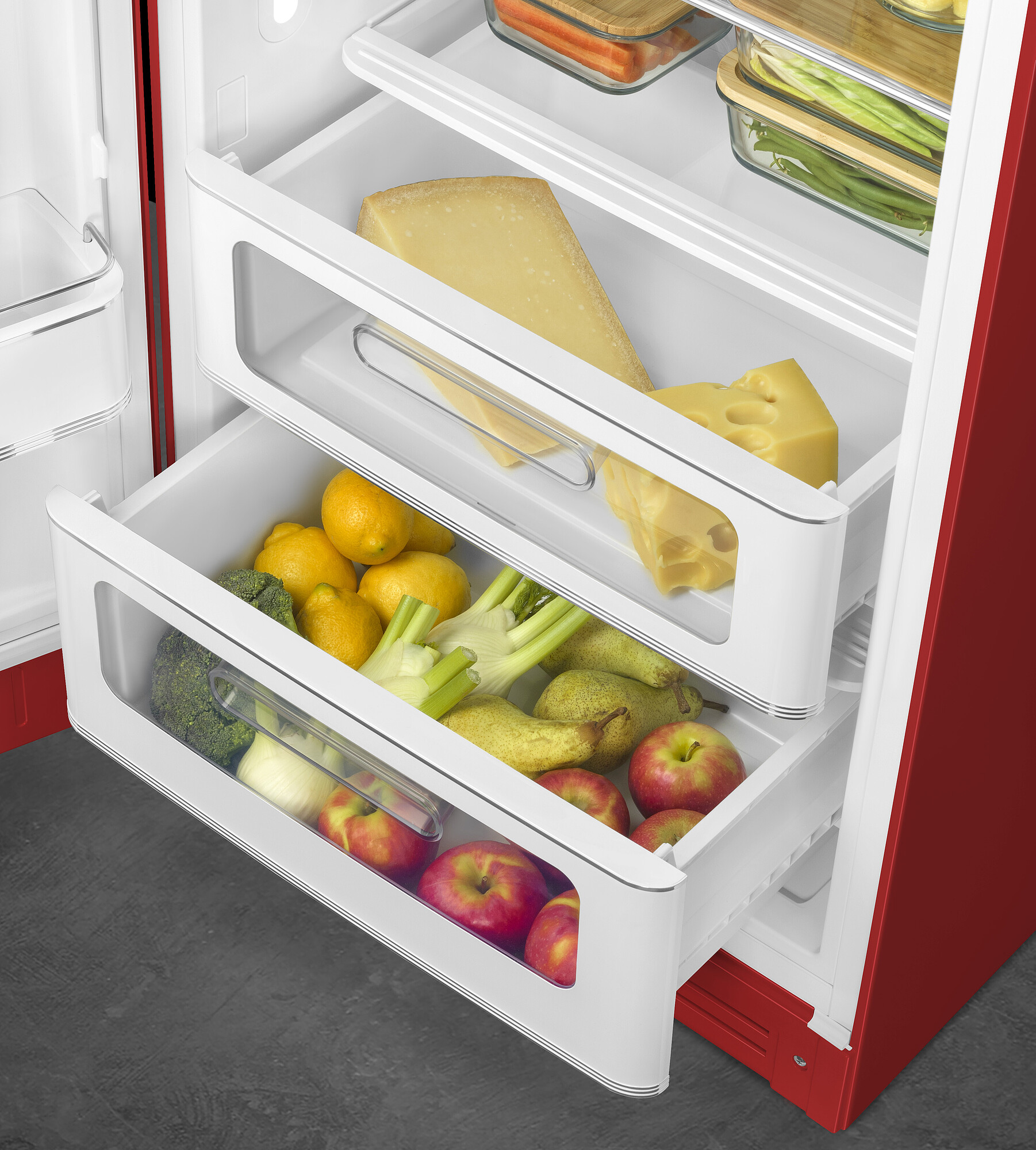 Offener Kühlschrank mit Käse, Zitronen, Äpfeln, Birnen, Fenchel und Brokkoli. Roter und weißer Innenraum mit grauem Boden.